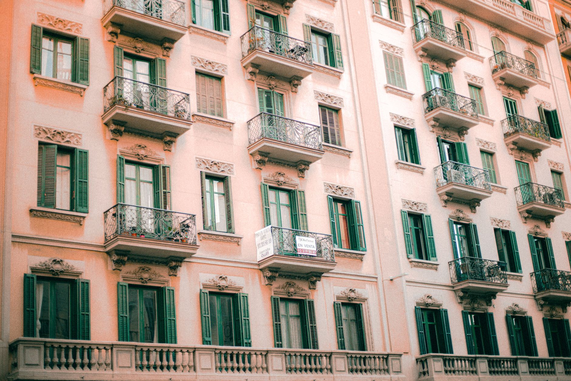 European-style building with ornate balconies and green shutters, capturing classic urban architecture.
