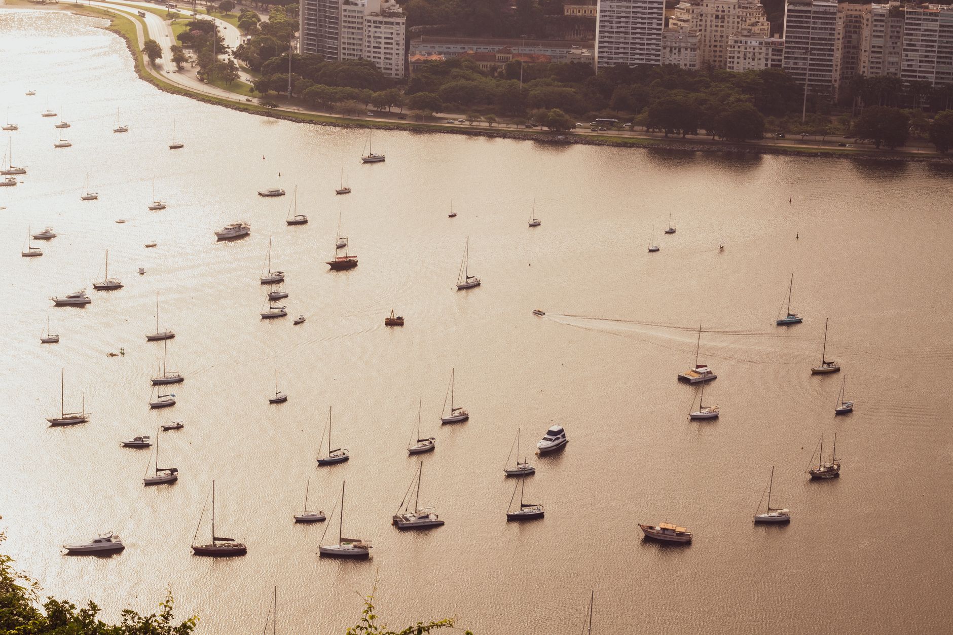 Aerial view of boats scattered across Guanabara Bay at sunset in Rio de Janeiro, Brazil.