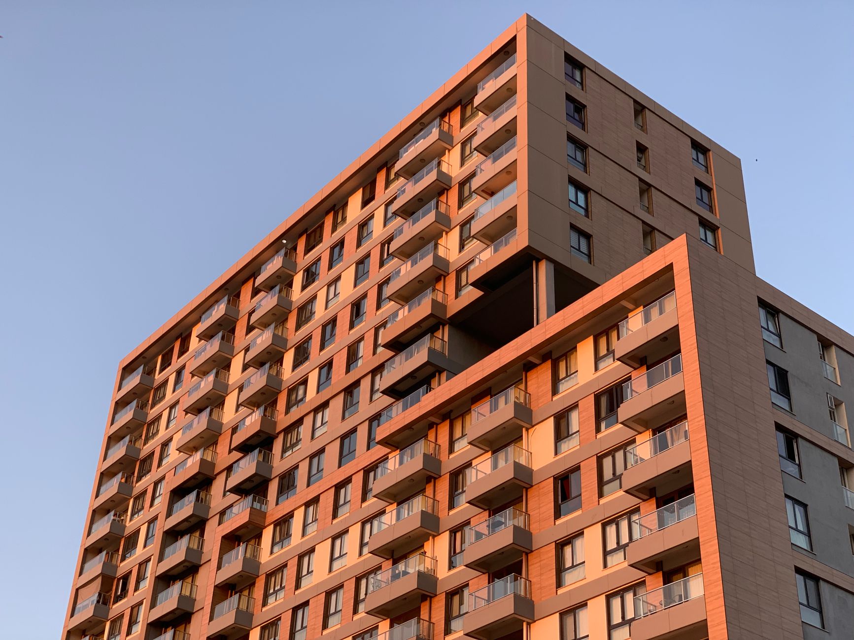 Contemporary apartment complex with balconies lit by sunset.