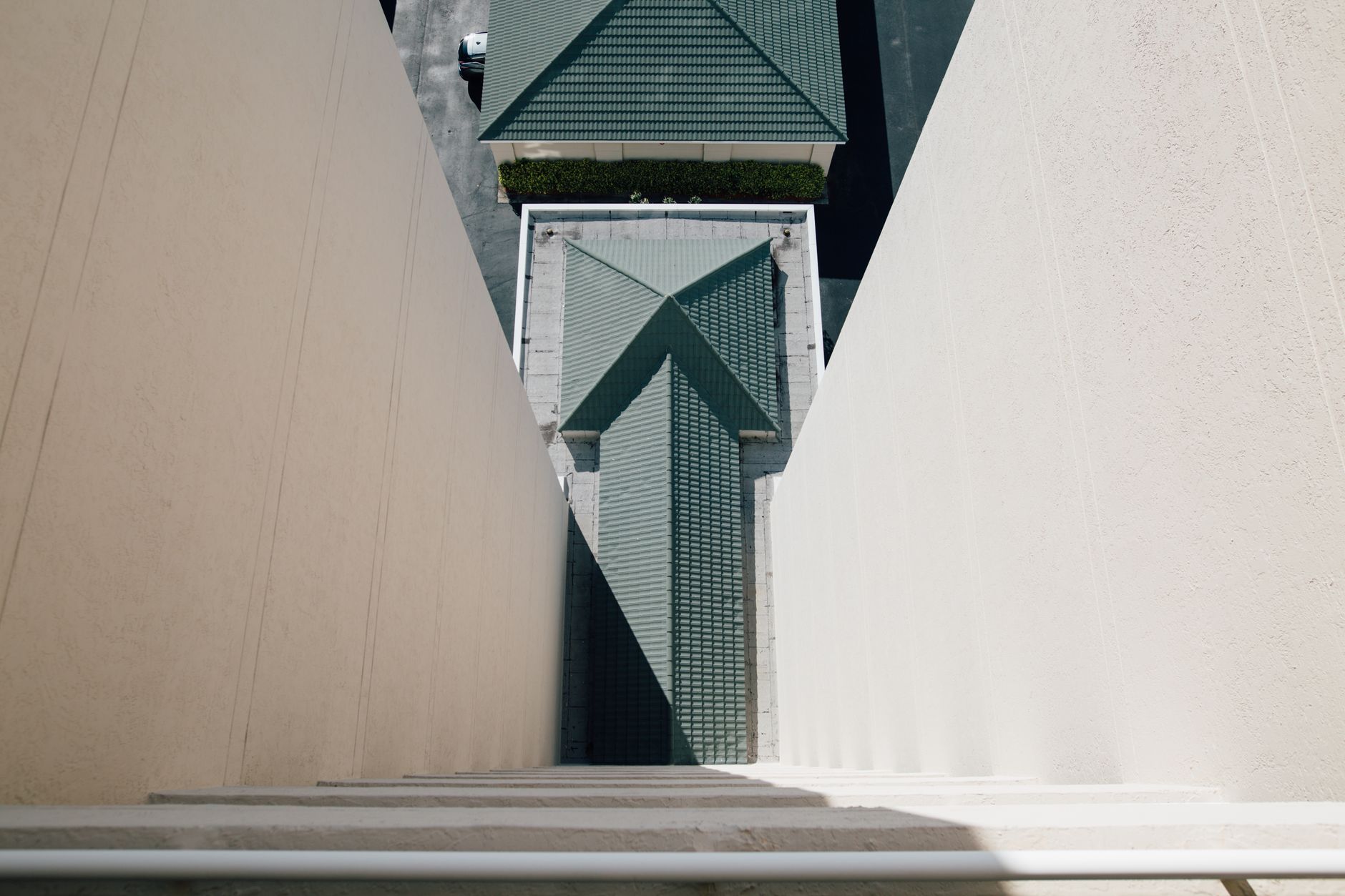 From  above of concrete walls and green tile roof of modern building on sunny day