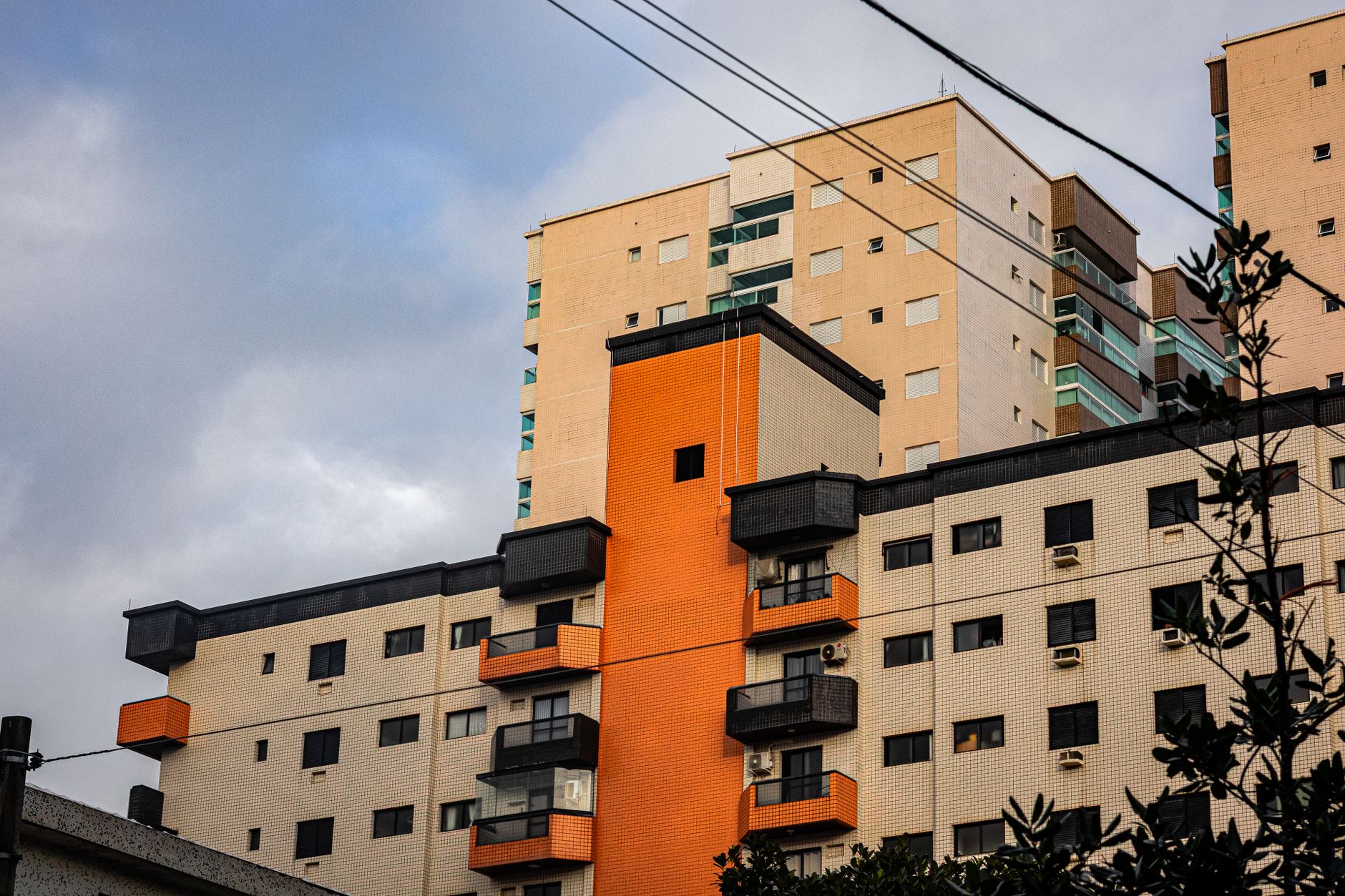 High-rise apartment building with modern architecture and contrasting colors under a cloudy sky.