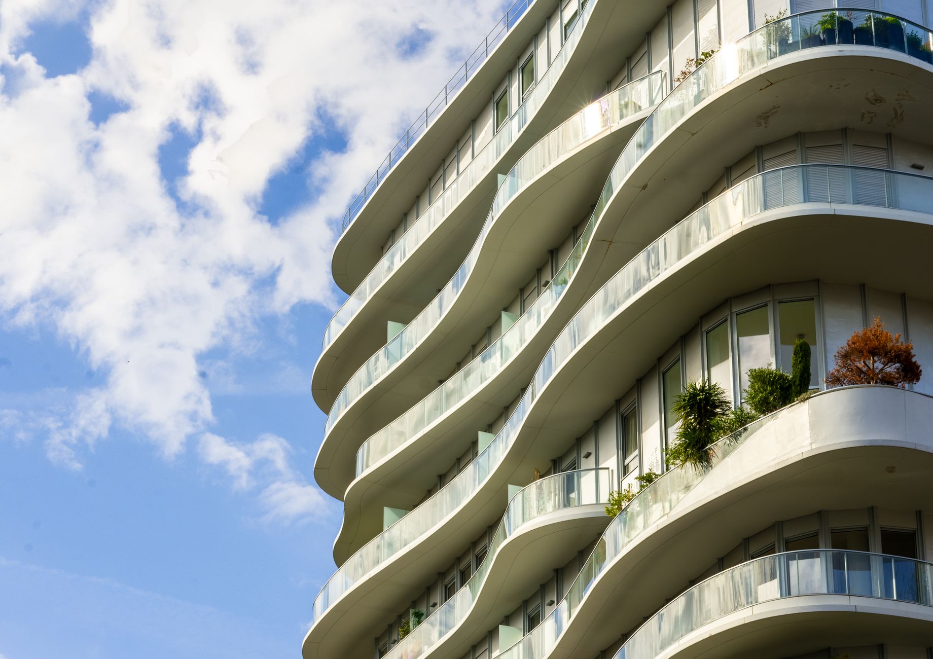Stylish curved apartment building in Paris with glass balconies against a blue sky.