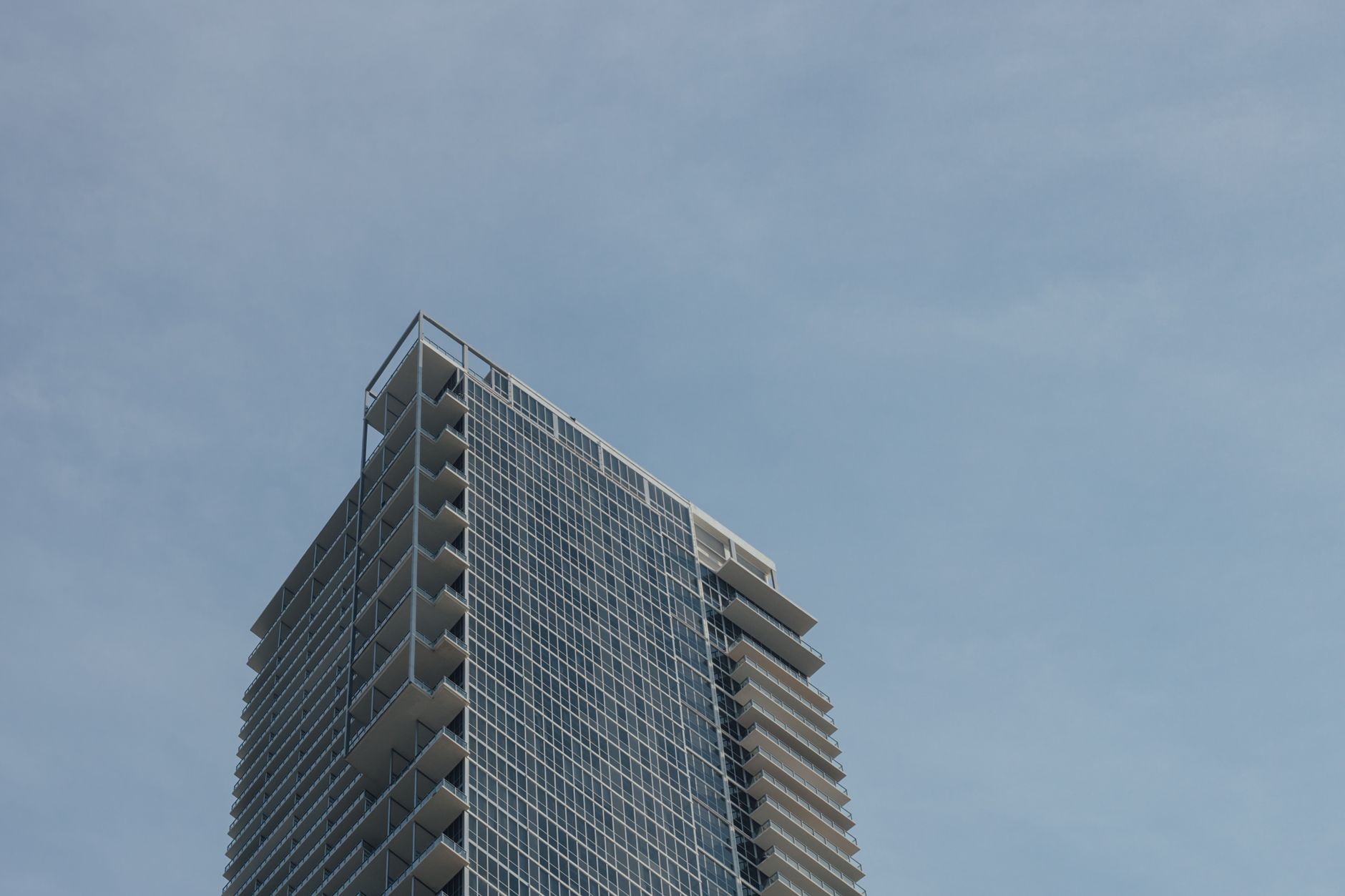 Low angle view of a modern skyscraper with balconies against a clear blue sky.