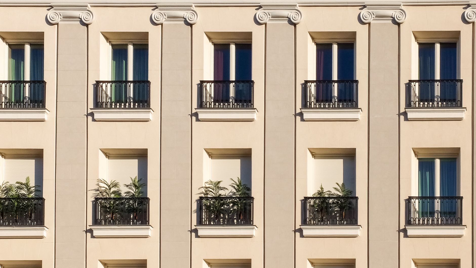 Elegant building exterior with classic windows and balconies adorned with plants.