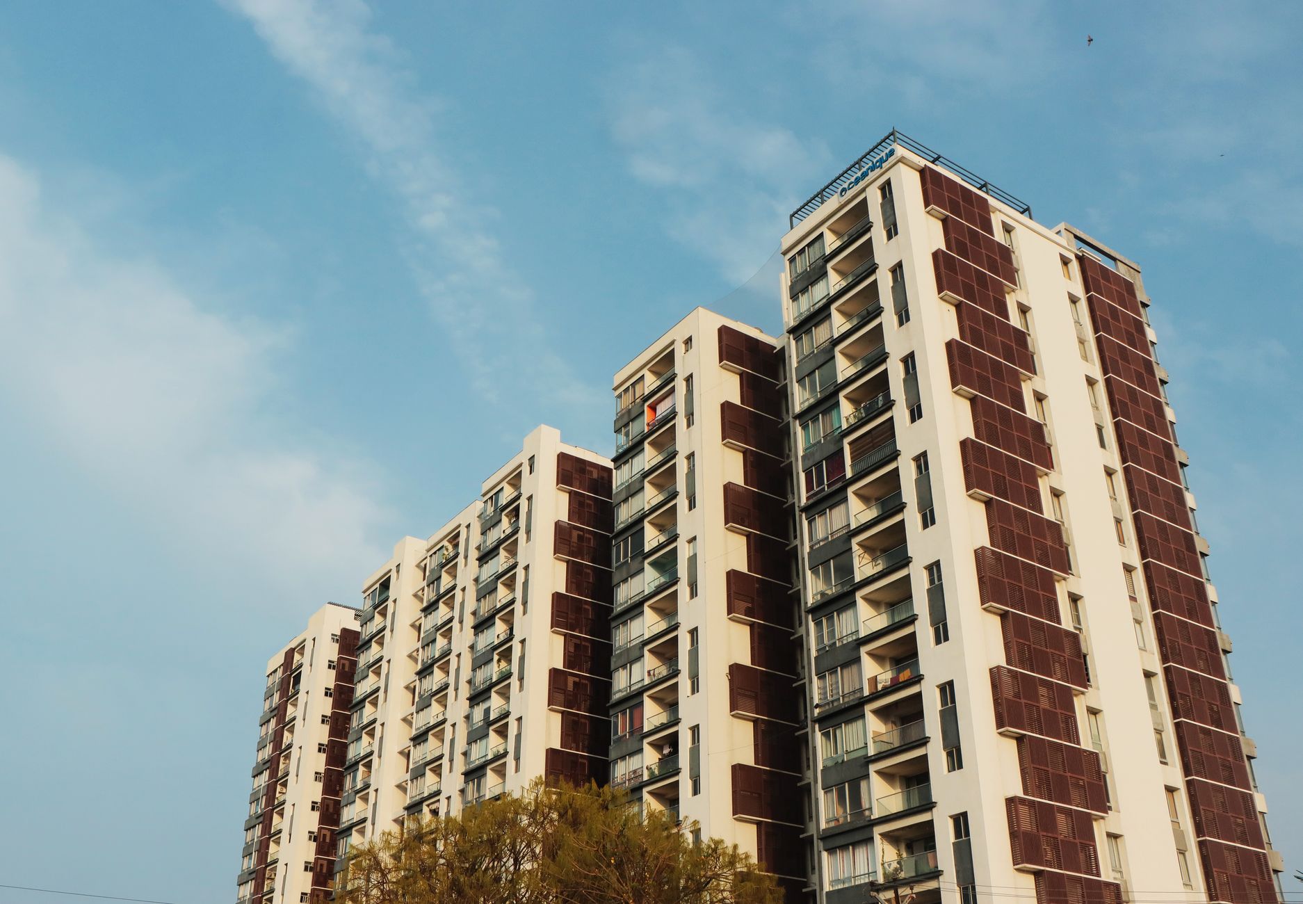A striking high-rise apartment building set against a clear blue sky, showcasing urban architecture.