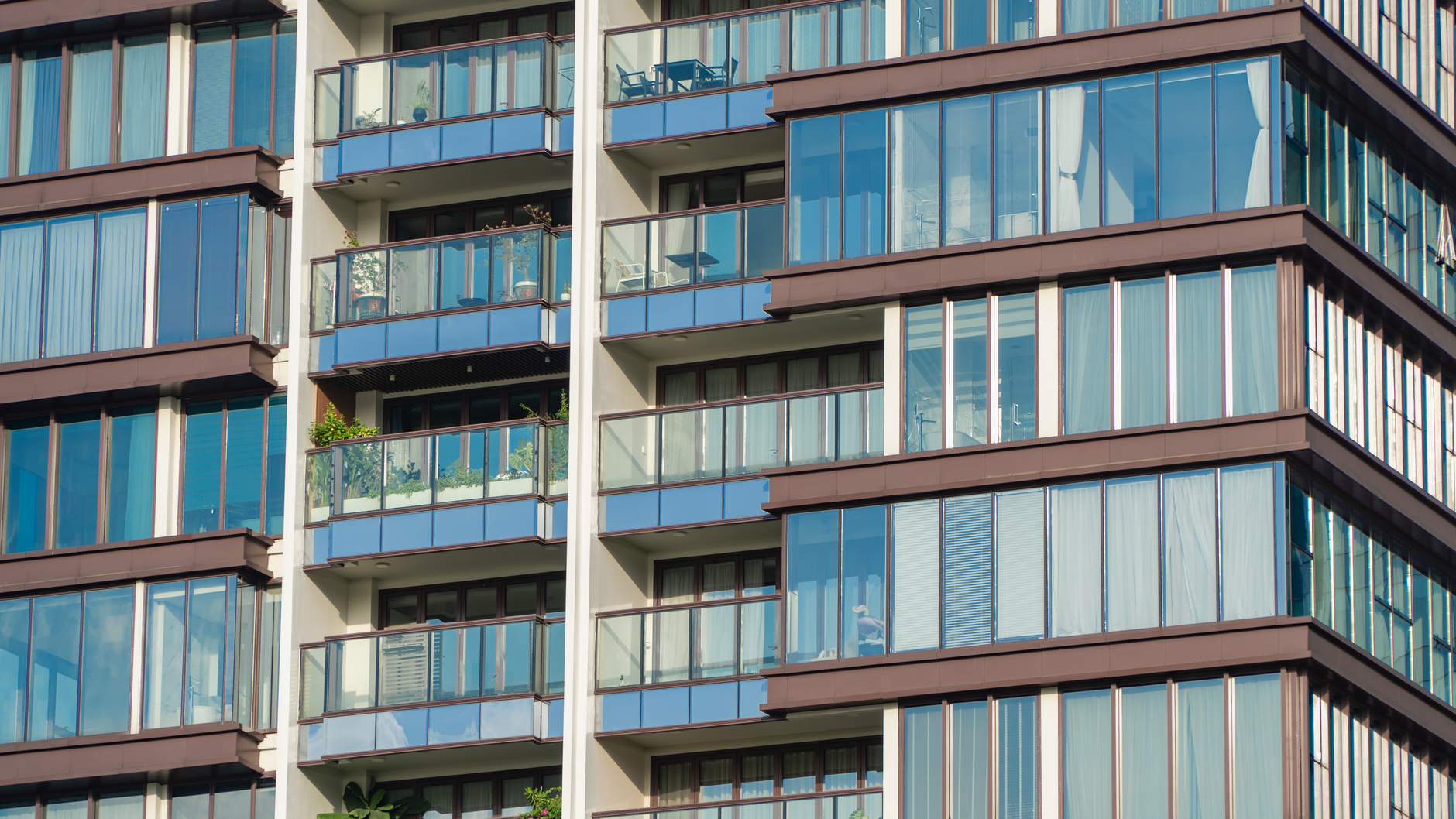 Close-up view of modern glass apartment facade with balconies and reflections.