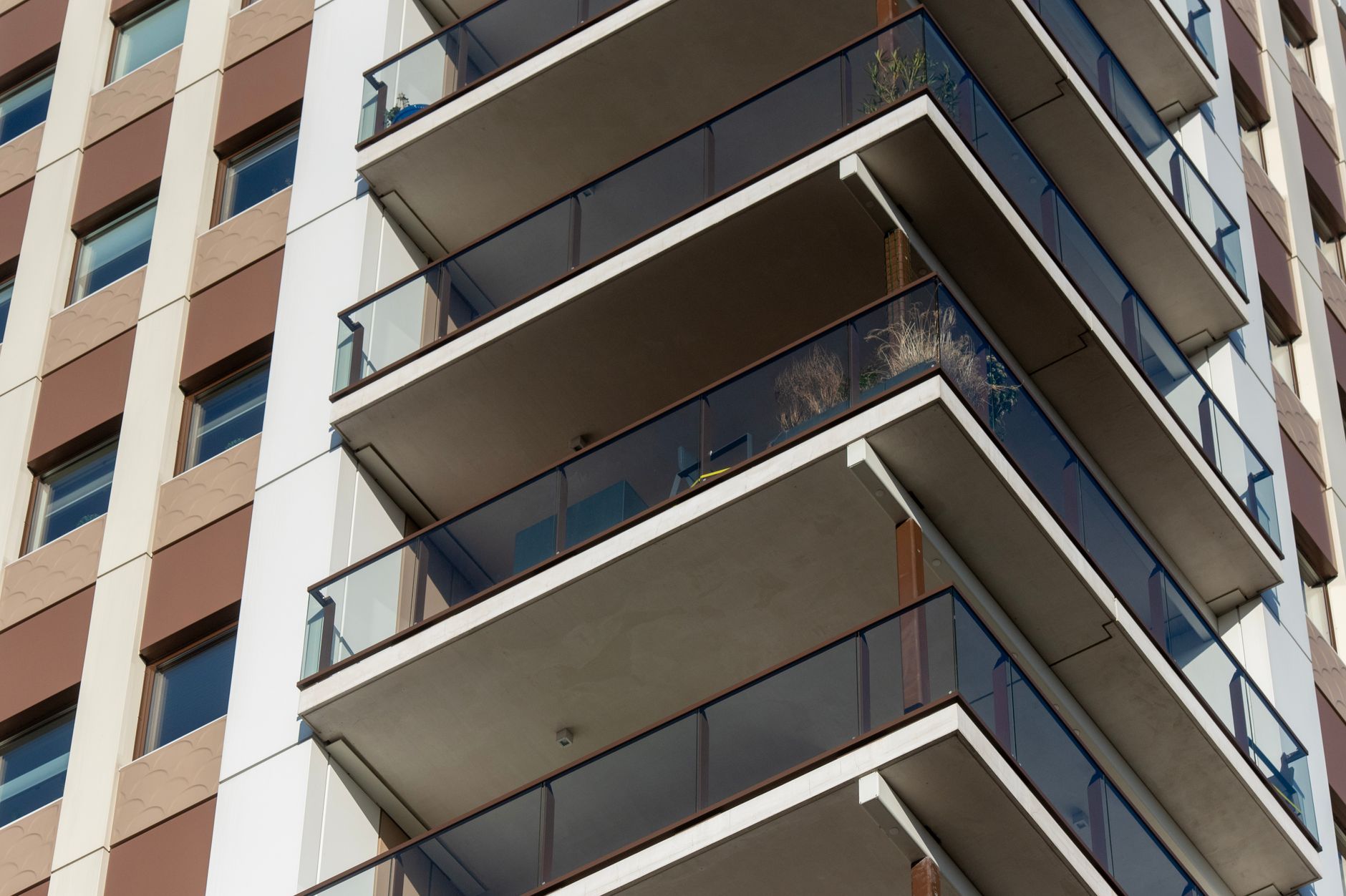 A detailed view of the balconies of a modern high-rise apartment building with glass railings.