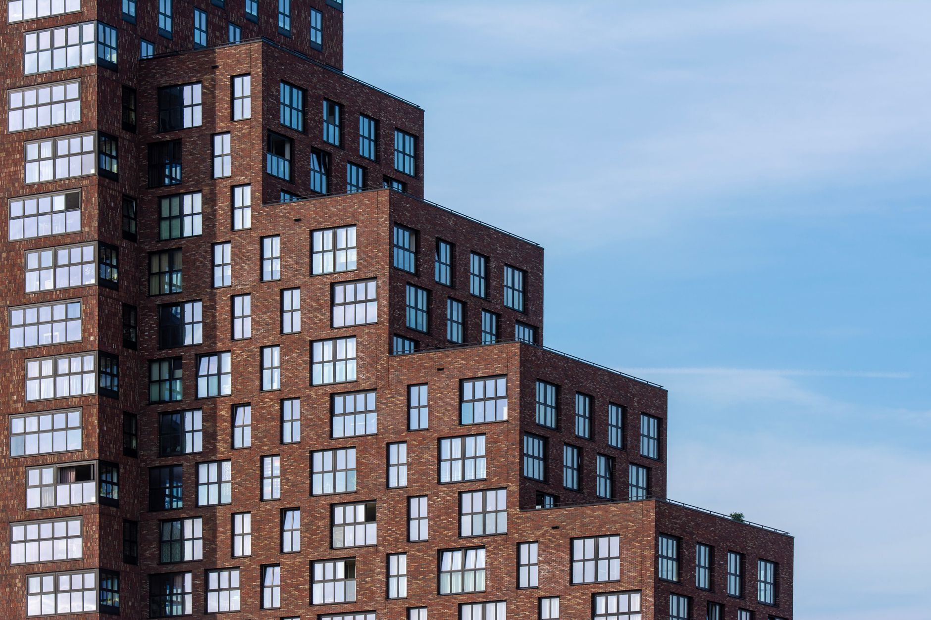 Brick facade of a modern residential building against blue sky.