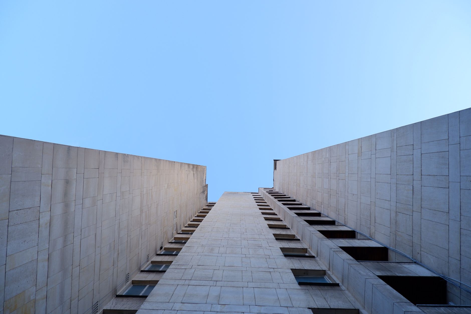 Looking up the facade of a skyscraper against a clear blue sky in Sofia, Bulgaria.