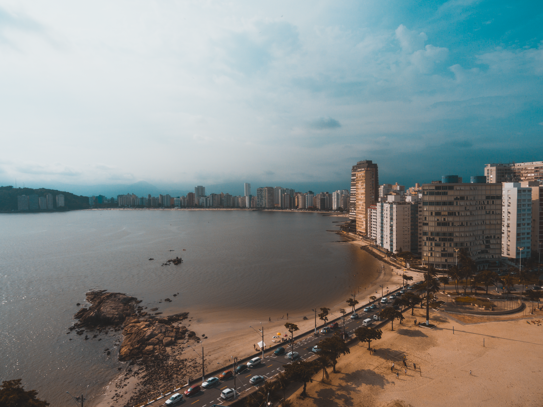 Stunning aerial view of a city's beachfront skyline with sandy beaches and calm waters under a cloudy sky.