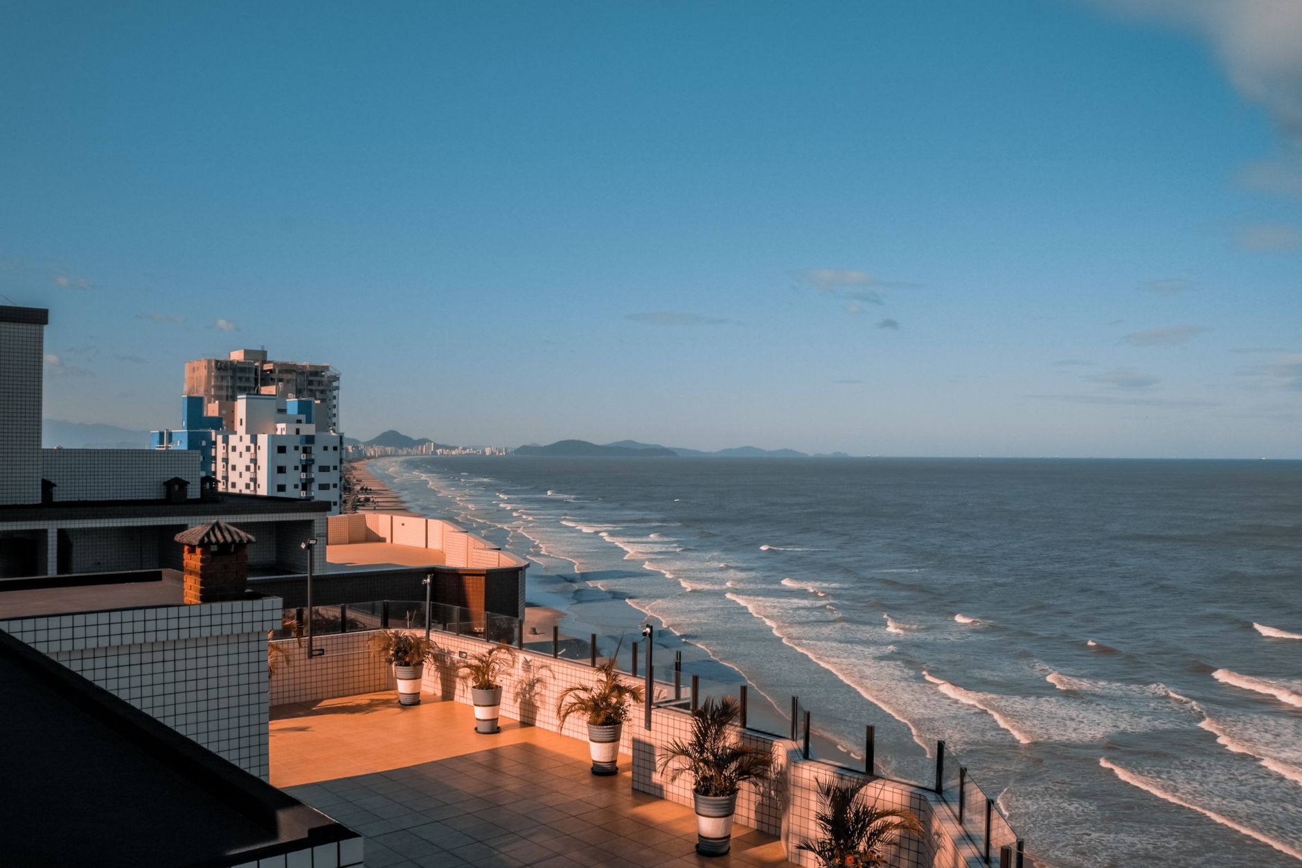 Scenic view of the coastline with urban buildings and the ocean under a blue sky.