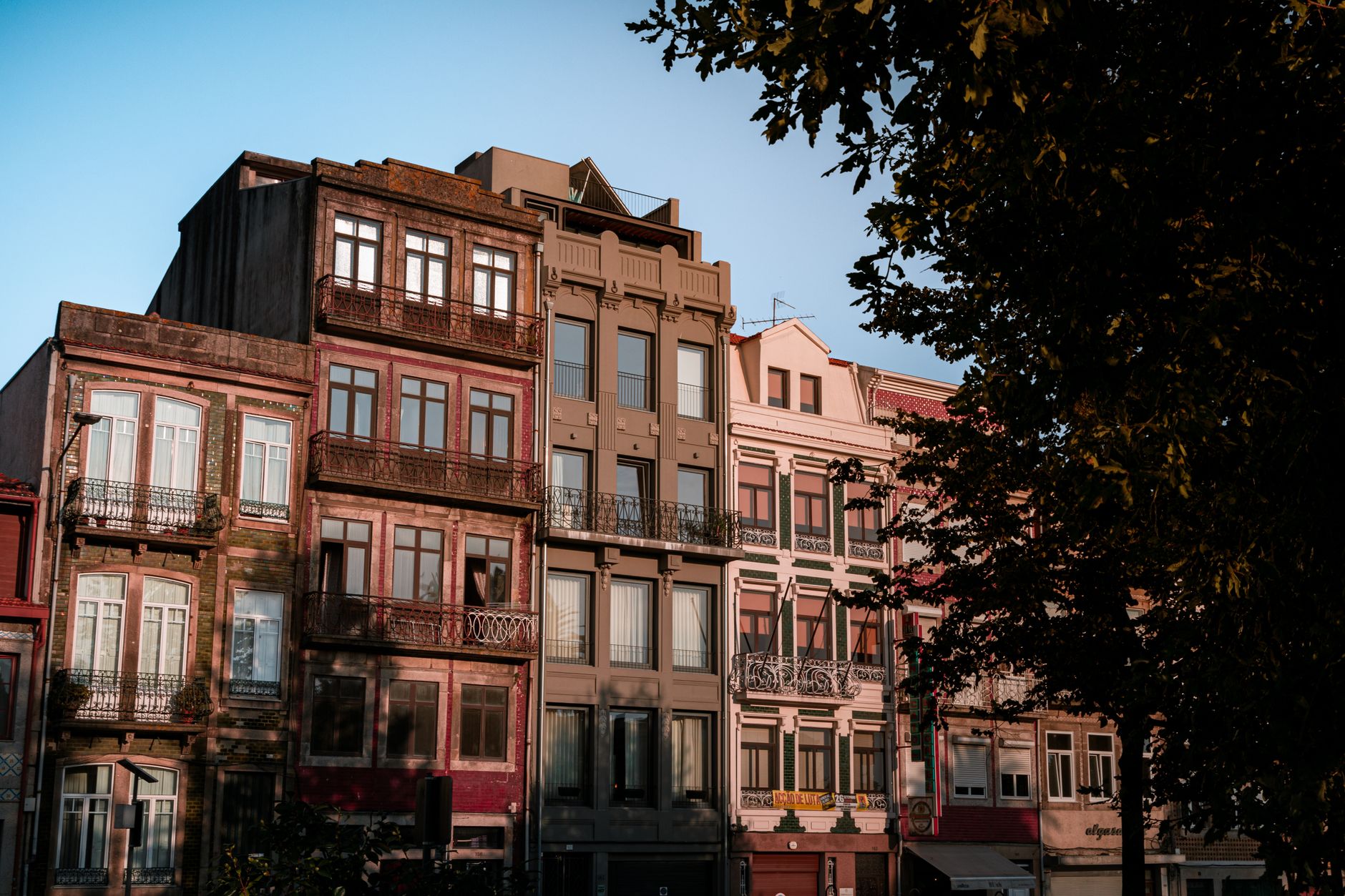Row of old urban apartment buildings with balconies, captured during sunset, highlighting architectural details.