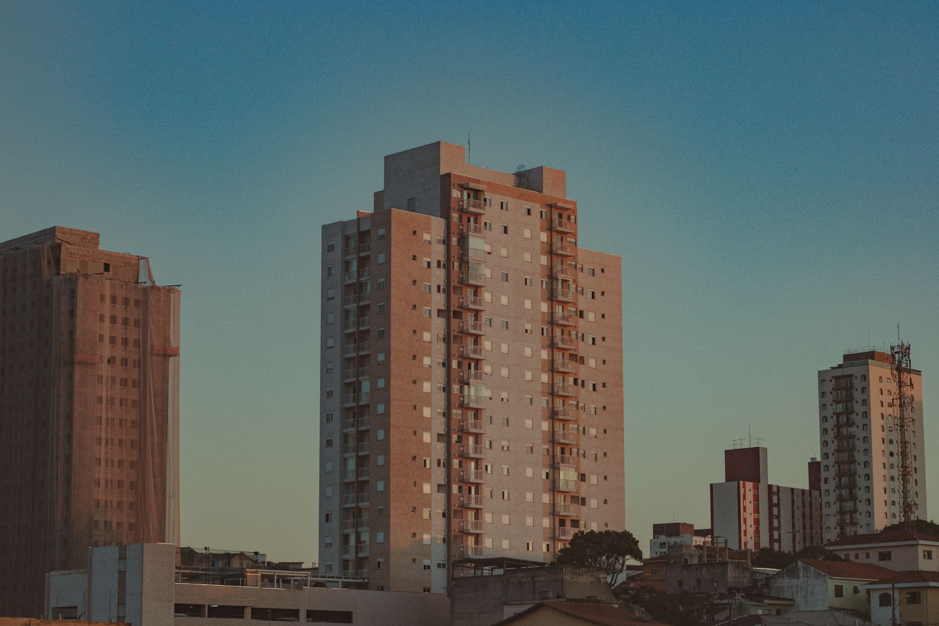 Captured urban skyline featuring modern high-rise buildings under a serene blue sky during dawn.
