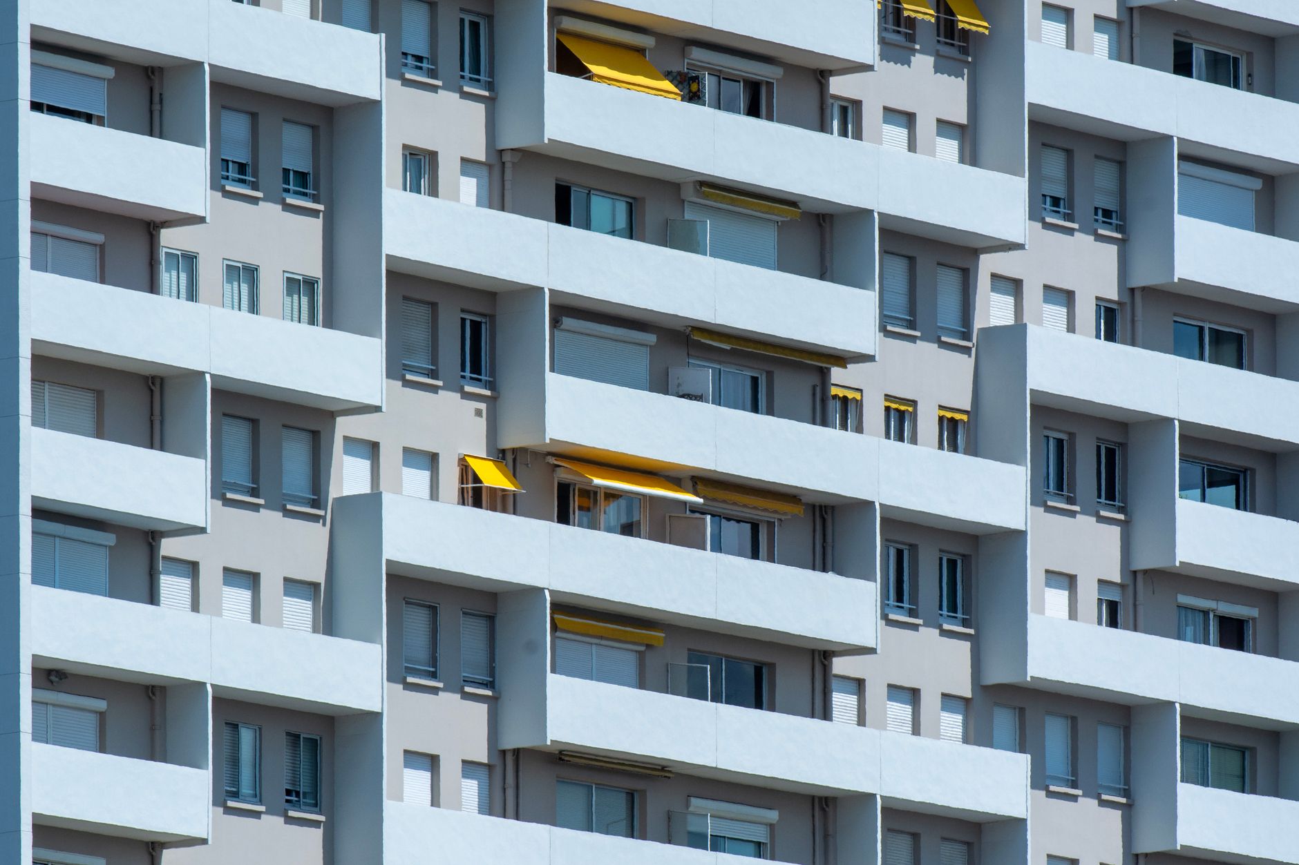 Close-up of a residential building facade with balconies and sunlight casting shadows.