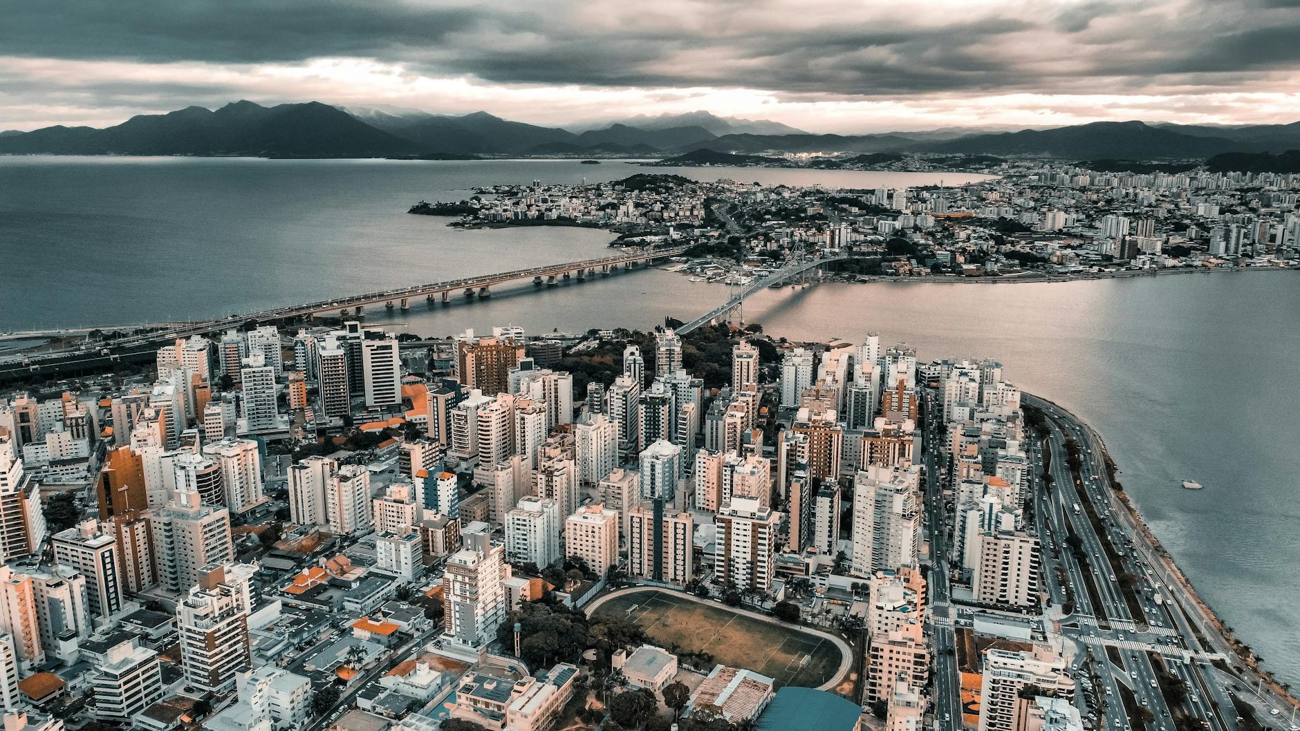 Stunning aerial view of Florianópolis cityscape with skyscrapers, bridge, and waterfront.
