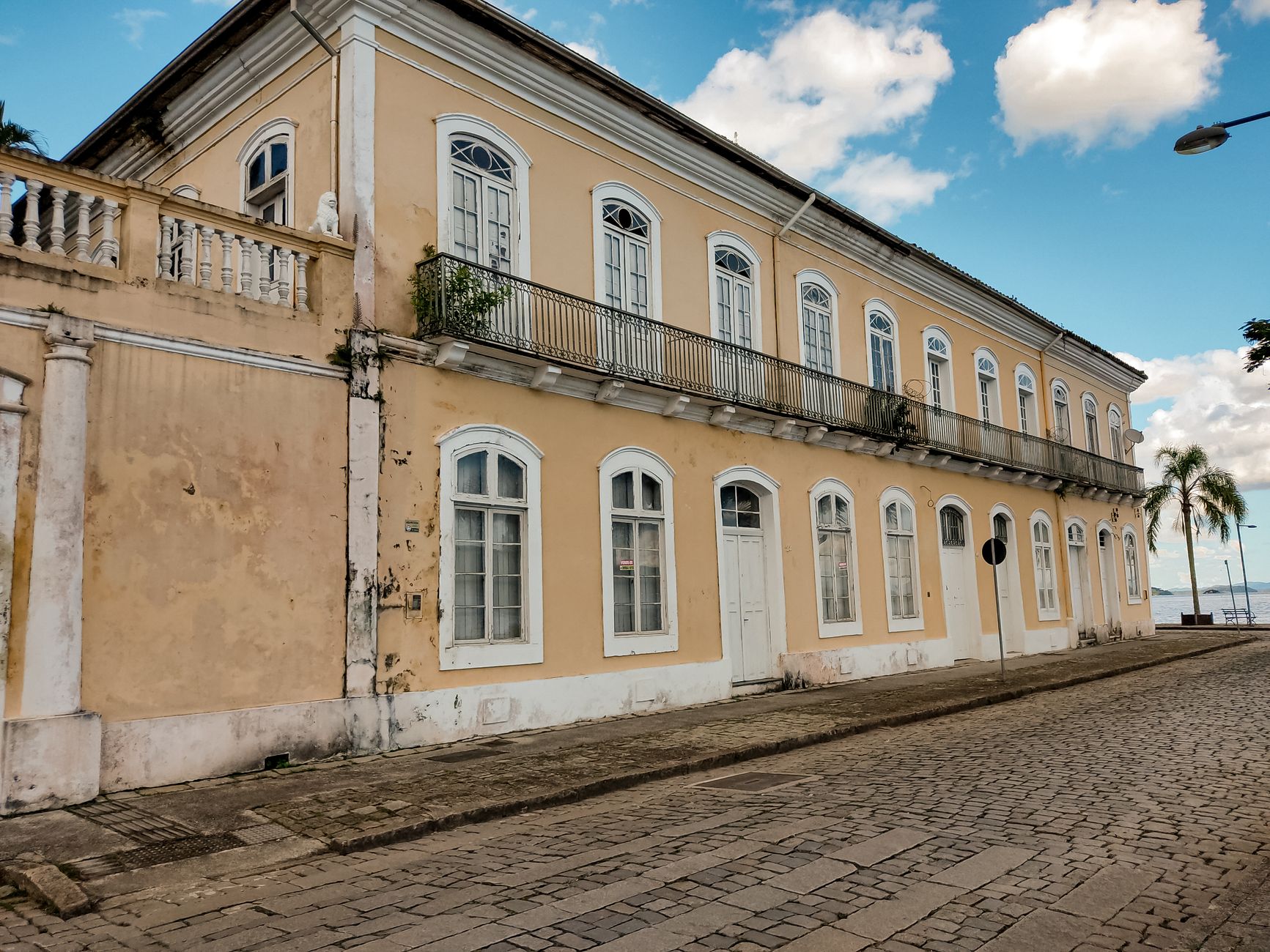 A beautifully detailed colonial building with arched windows, captured on a quiet cobblestone street.