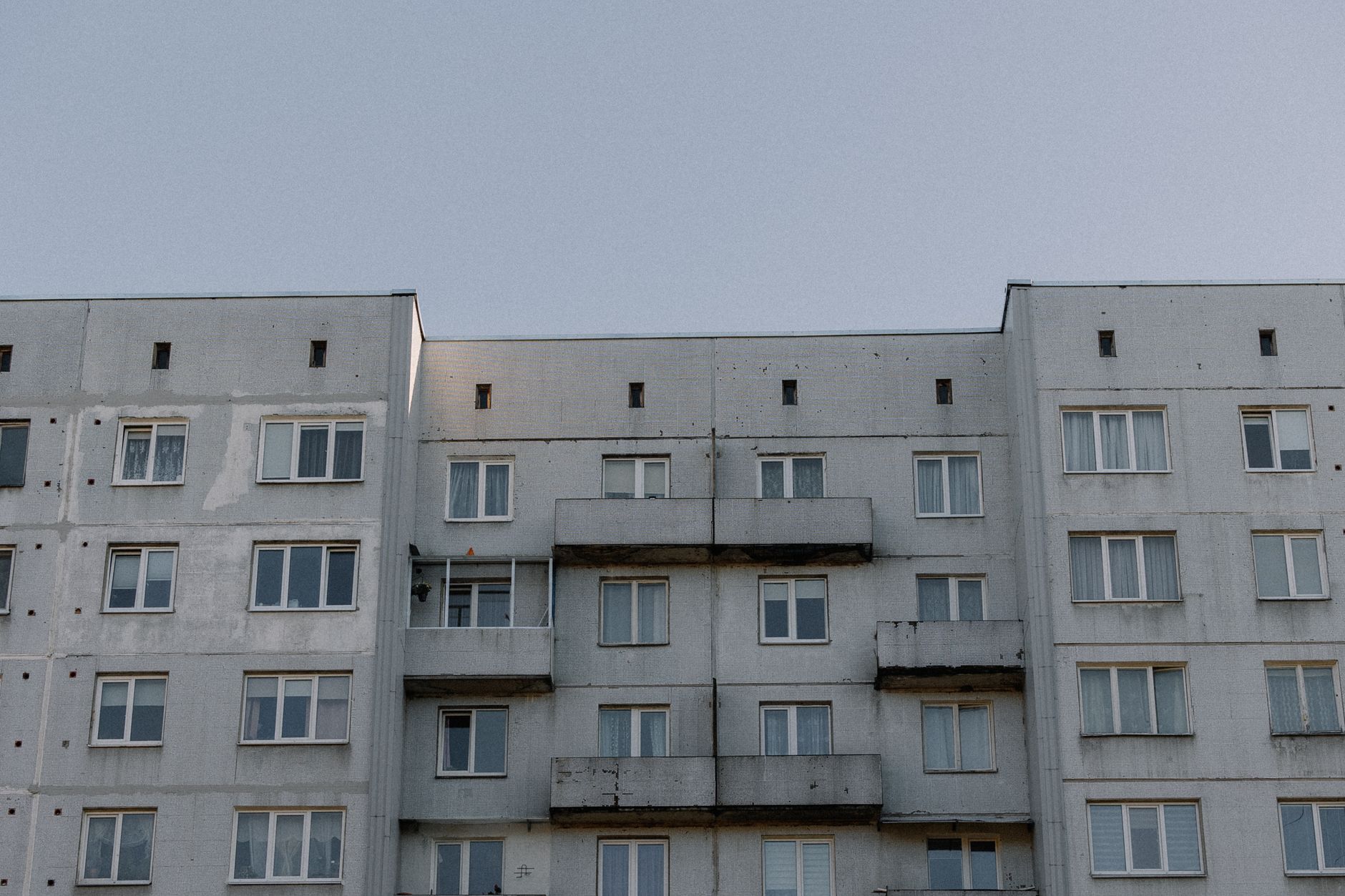 A concrete apartment building under a clear blue sky, showcasing urban architecture.