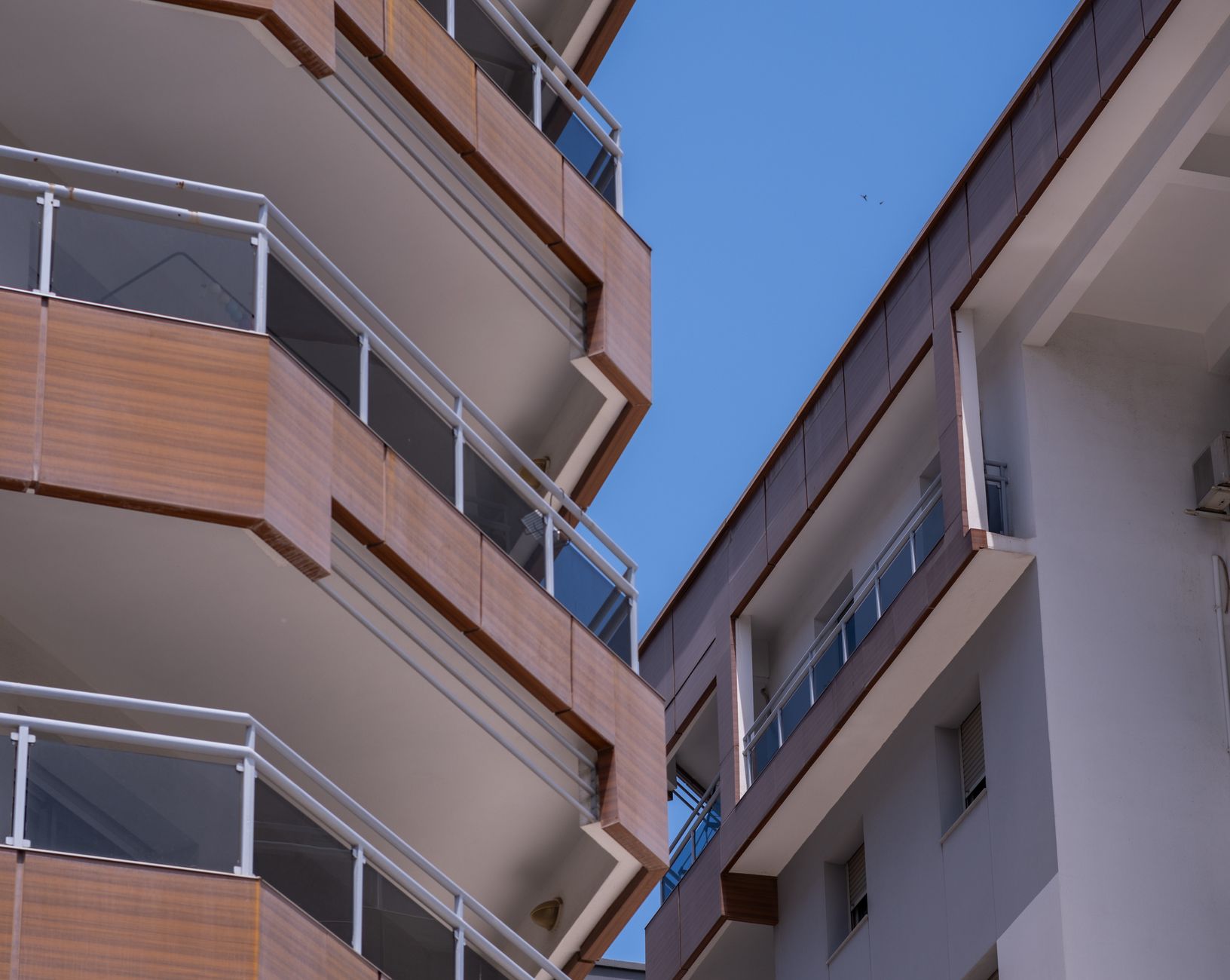 Close-up of modern apartment buildings in İzmir, highlighting architectural details and blue sky.