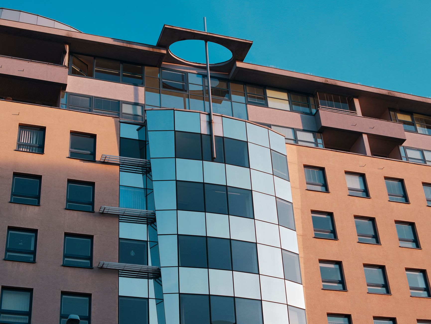 Close-up of a modern urban building facade with geometric design and reflective windows in sunlight.