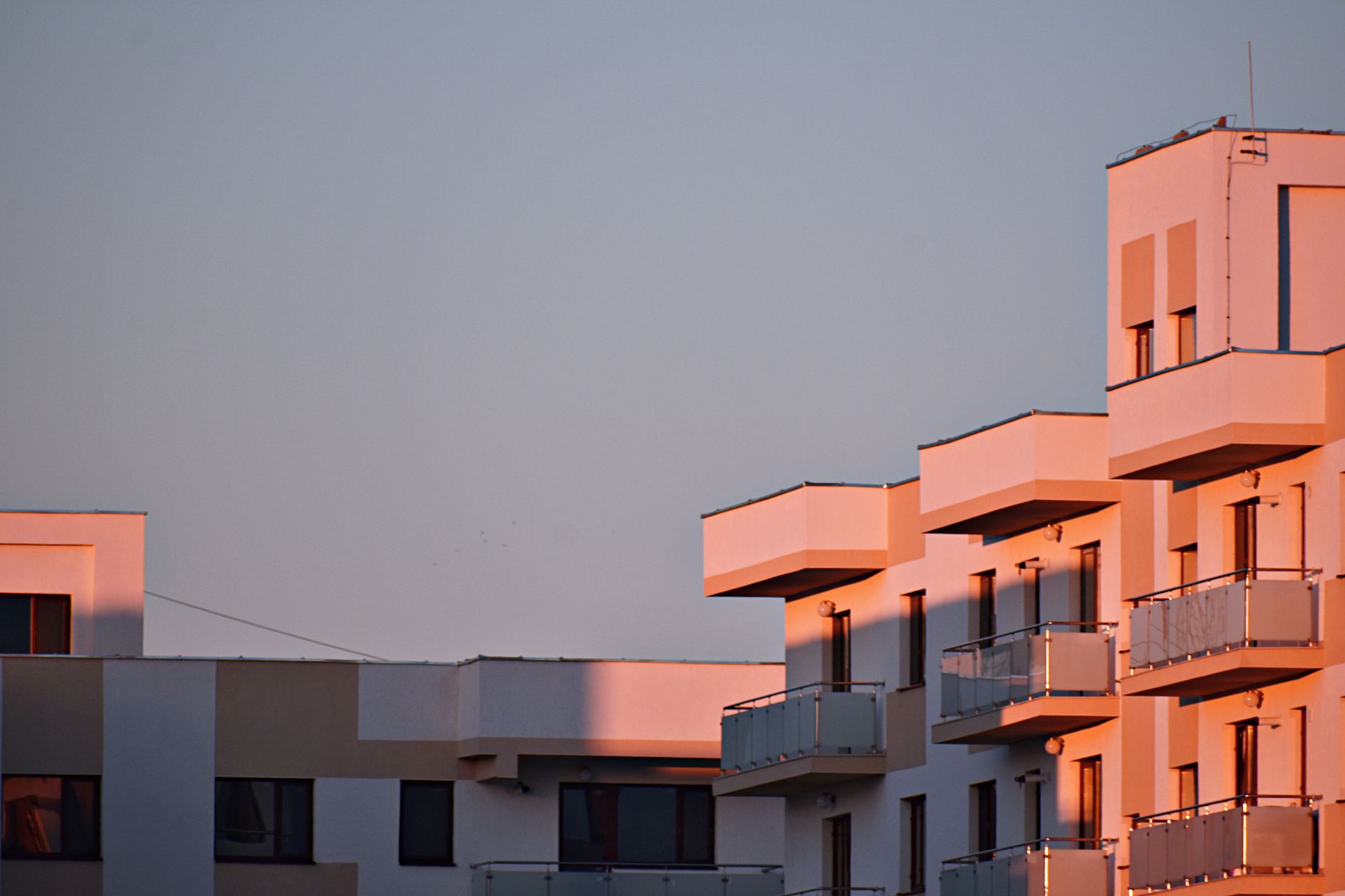 Modern apartment building with balconies bathed in sunset light.