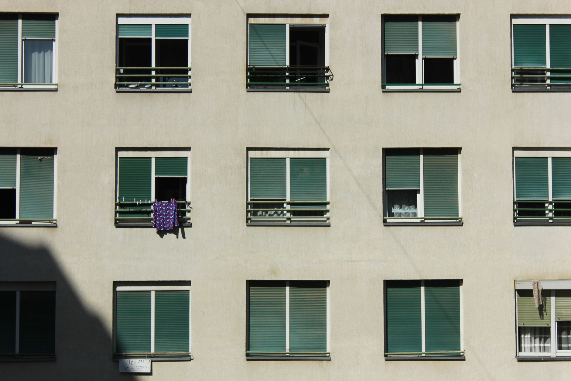 A minimalist view of a modern apartment building facade with repetitive window pattern.