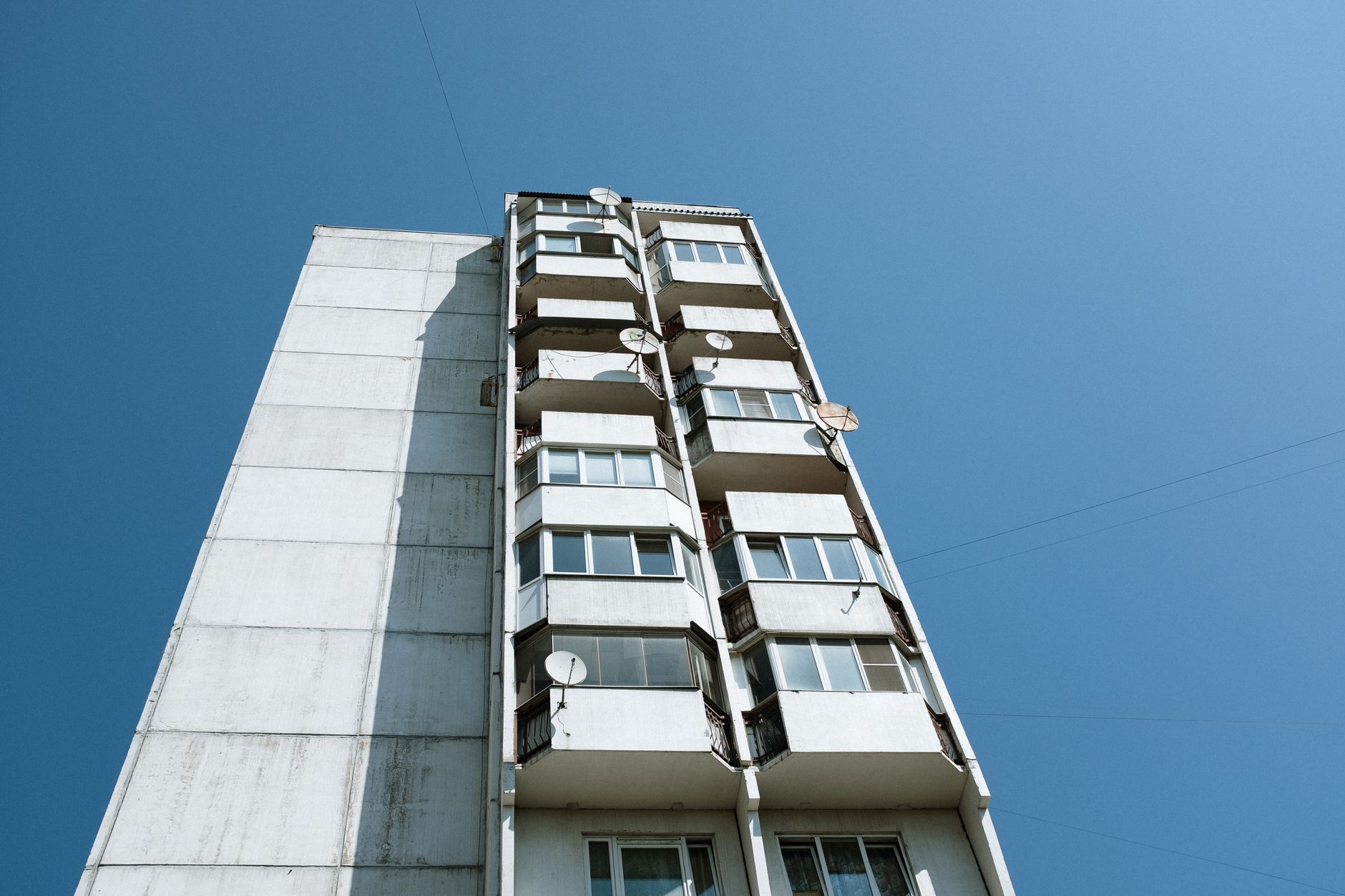 Low angle view of Soviet-style panel apartment building with blue sky backdrop.