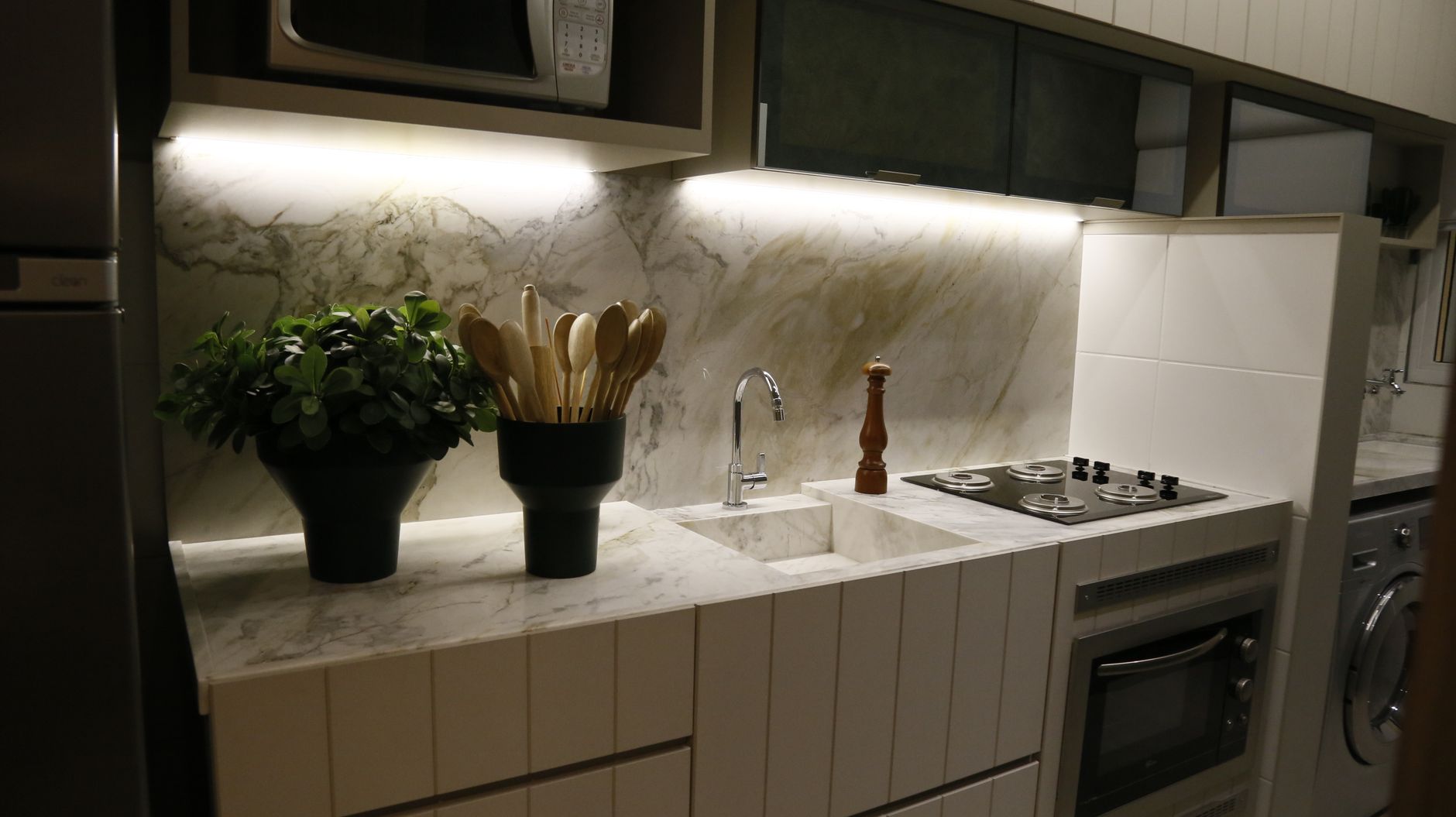 Stylish modern kitchen featuring a marble countertop, plants, and appliances.