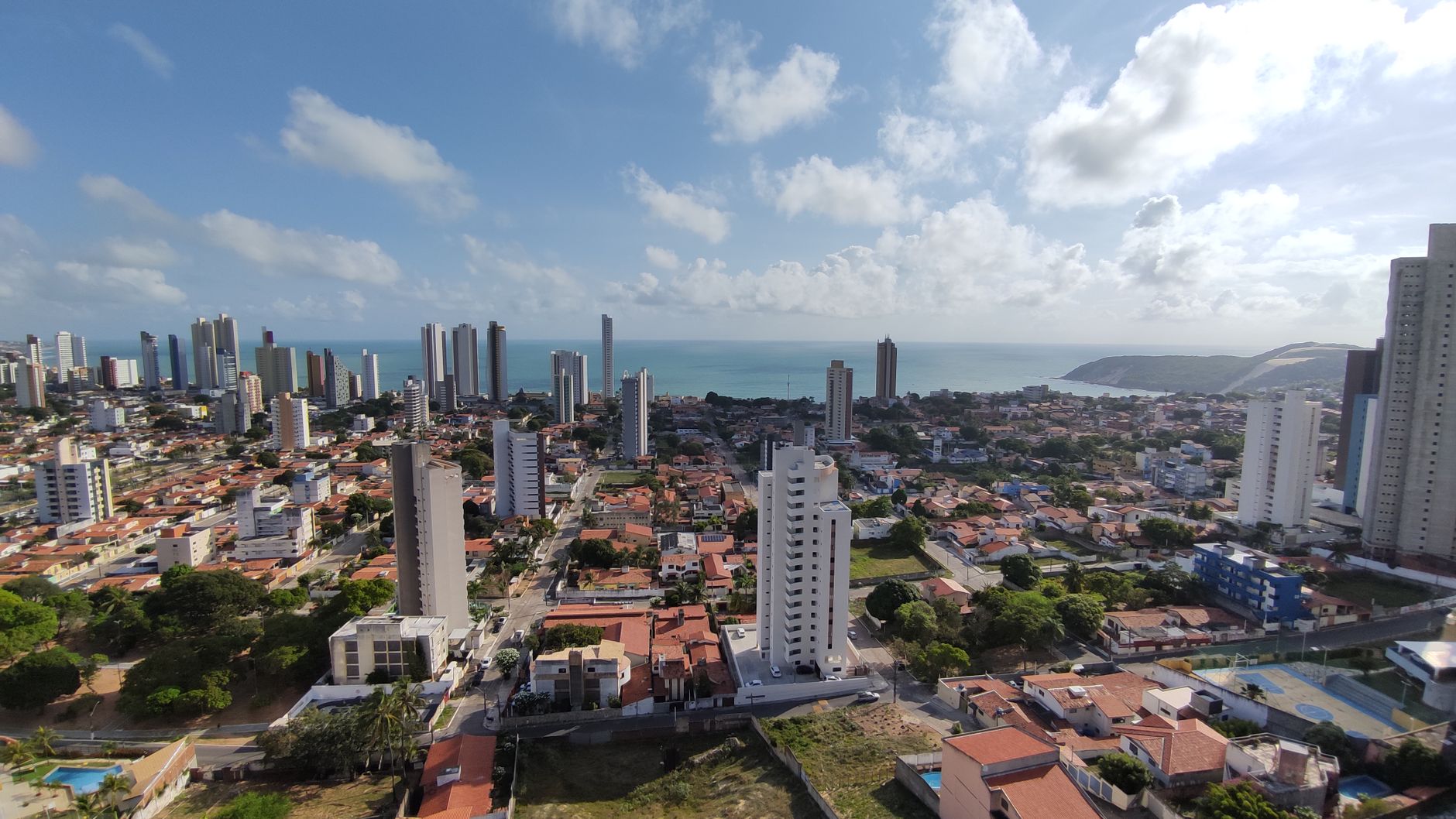 Aerial view of Natal, Brazil showcasing the skyline and Ponta Negra Beach under a sunny sky.