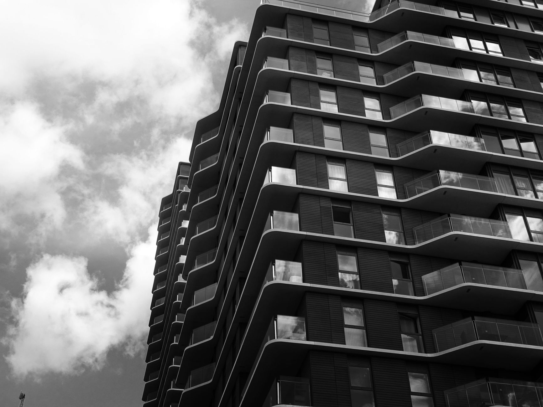 Black and white photo of a modern skyscraper with dramatic angles and clouds.