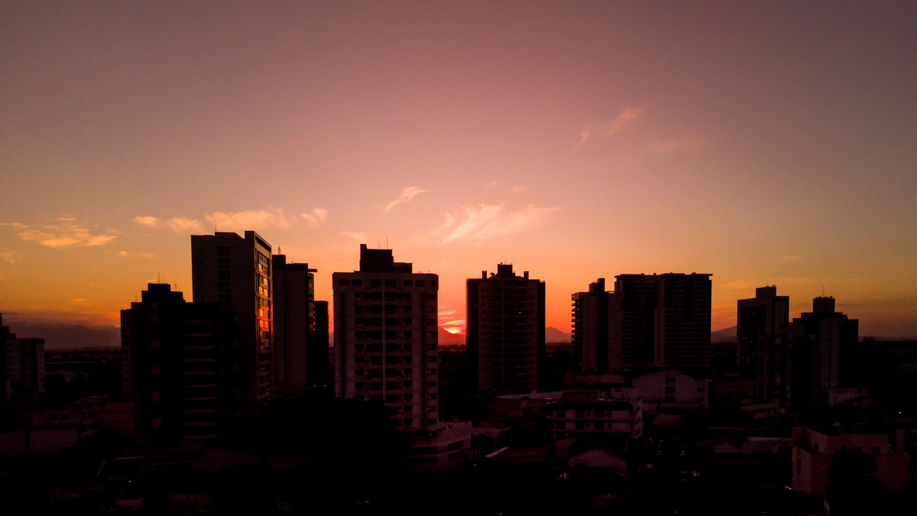 Stunning sunset view over Campos dos Goytacazes city skyline silhouettes.