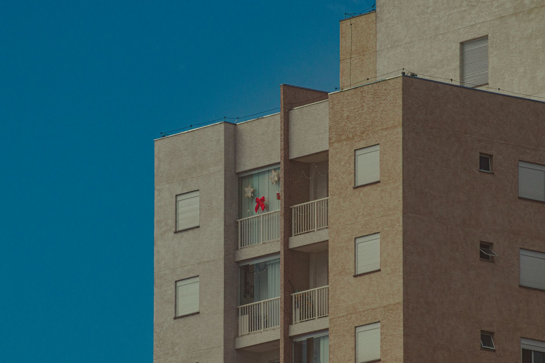 Low angle of concrete building with balconies with star and ribbon shaped decorations on window in residential district