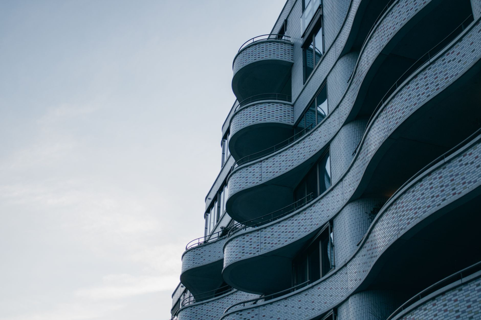 Captivating architectural design with unique curved facade and balconies against a clear sky.