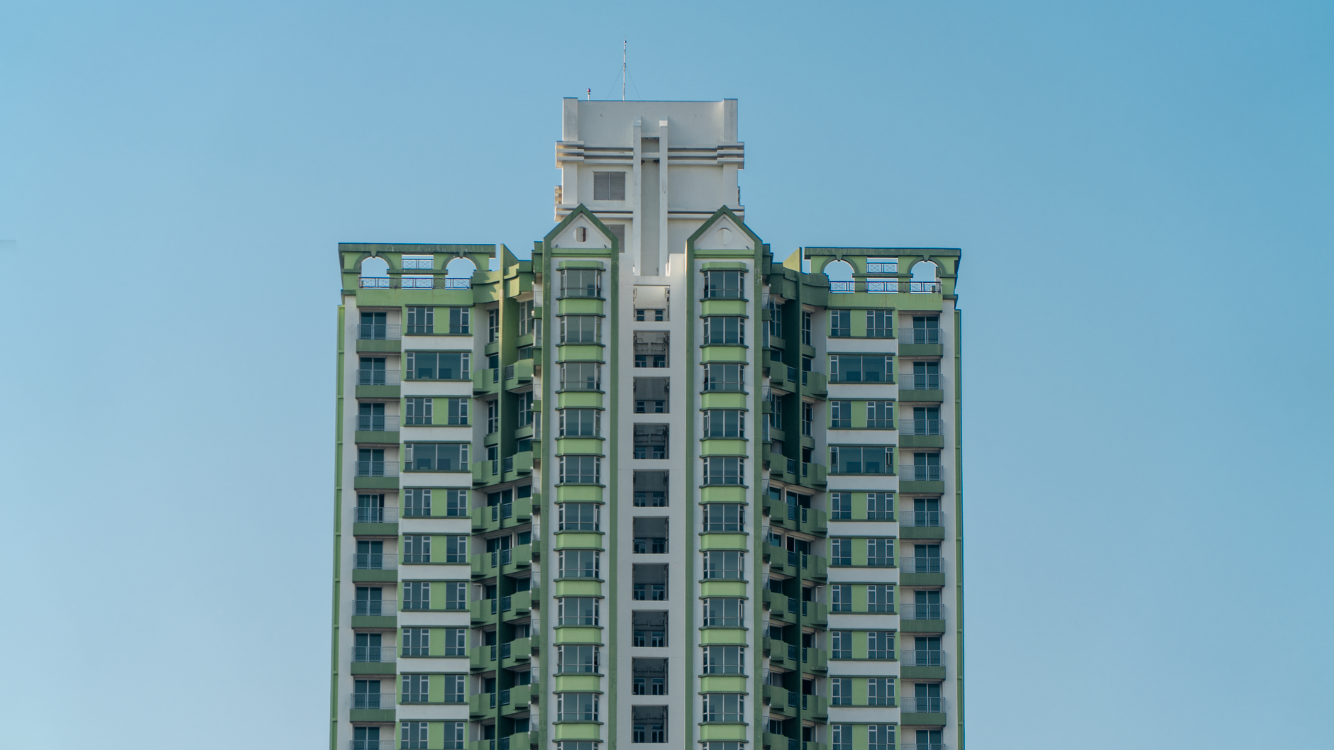 Vertical view of a modern high-rise building with architectural design against a clear blue sky.