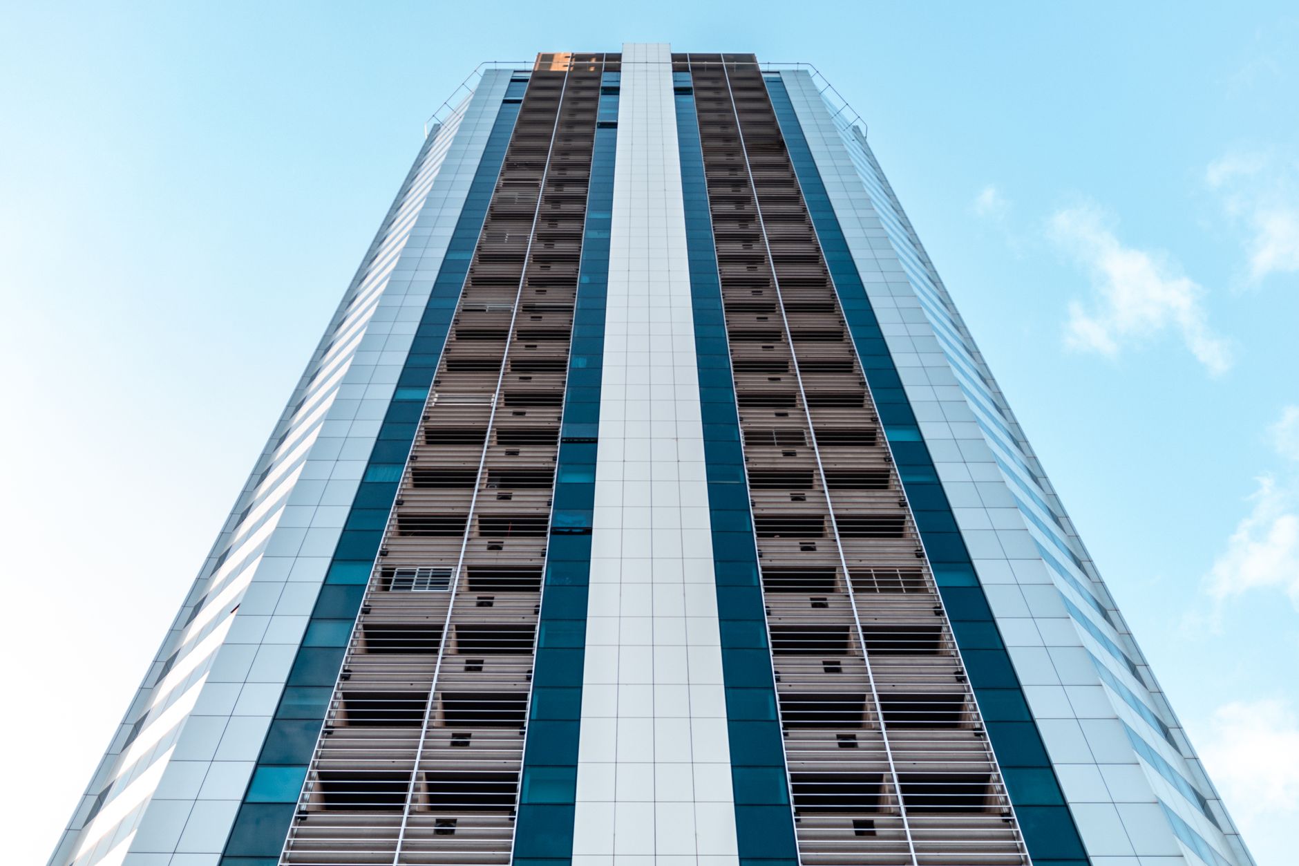 Low angle view of a modern skyscraper with glass panels against a clear blue sky.