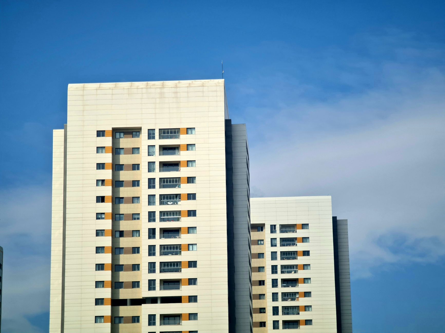 A modern high-rise building with a clear blue sky backdrop, showcasing architectural elegance.