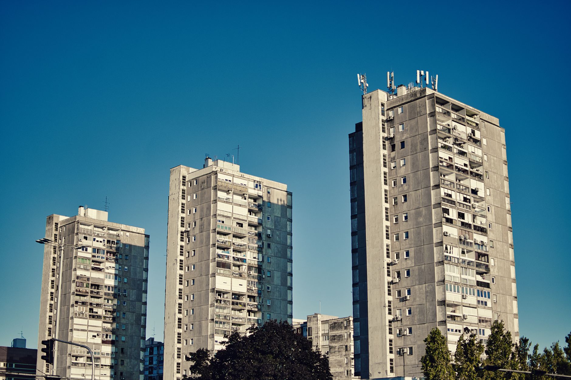 Row of tall urban apartment buildings against a clear blue sky, showcasing modern architecture.