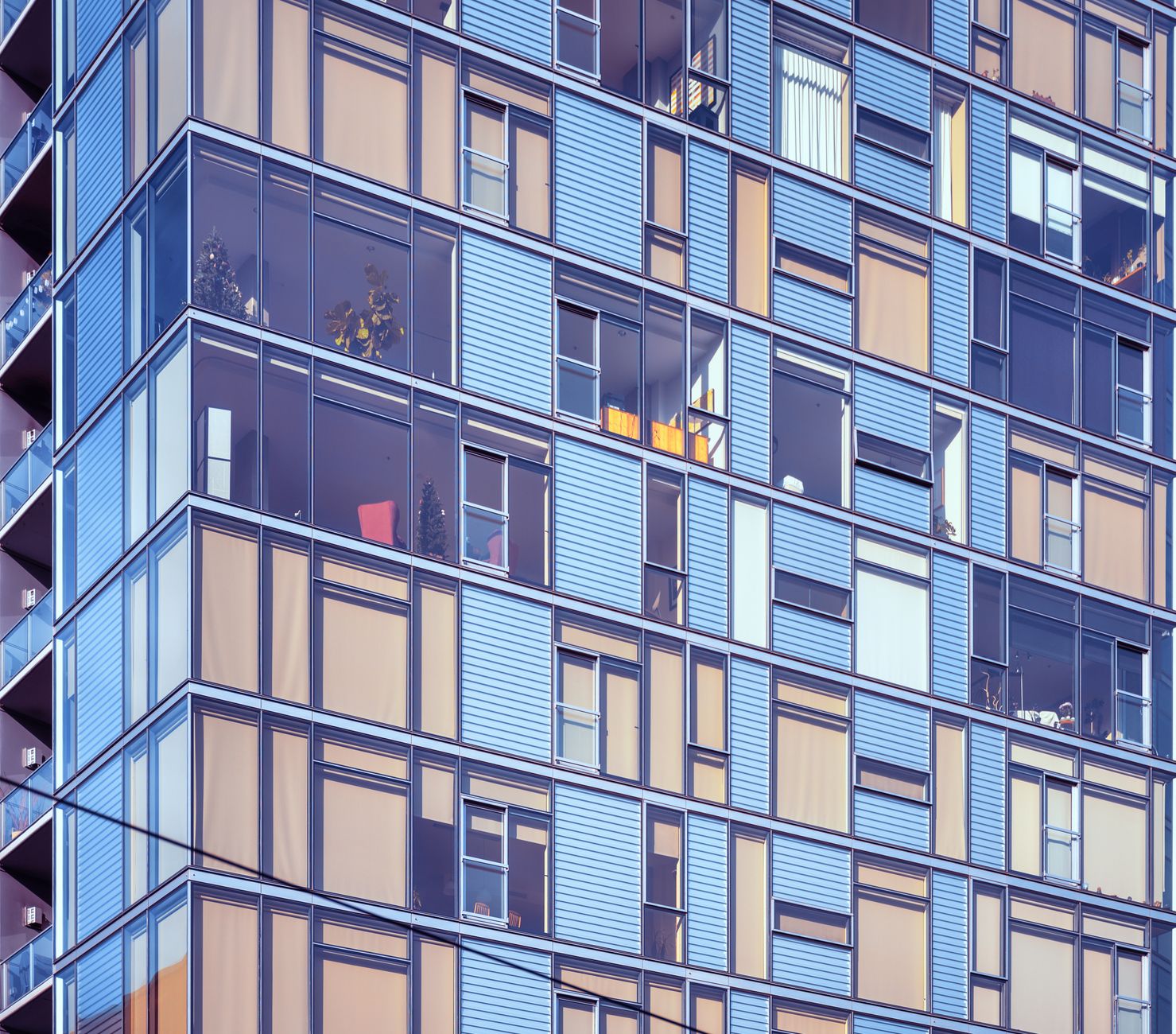 Facade of bright multistory apartment building with rolled curtain on big glass windows and balconies located on street in city