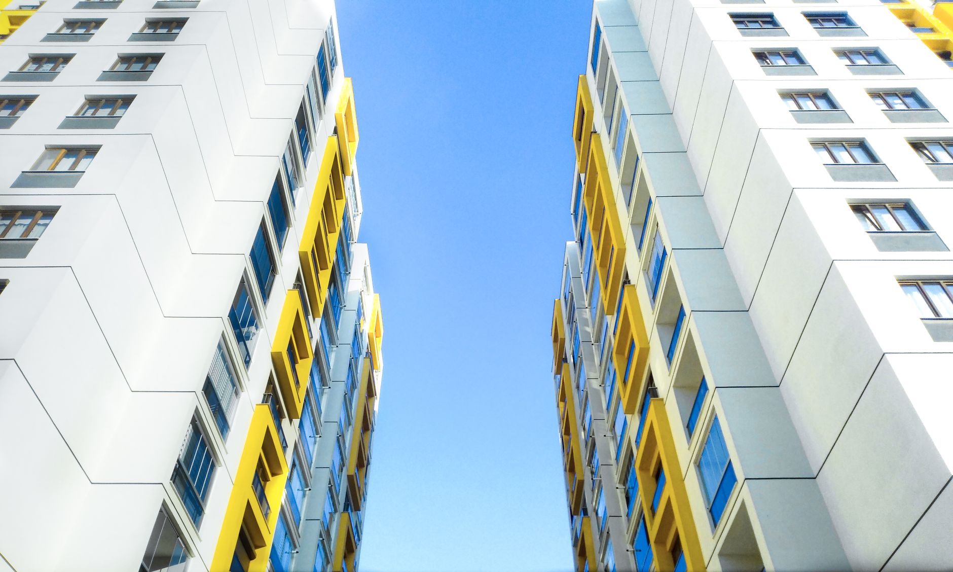 Low angle view of modern apartment buildings in Türkiye against a clear blue sky.