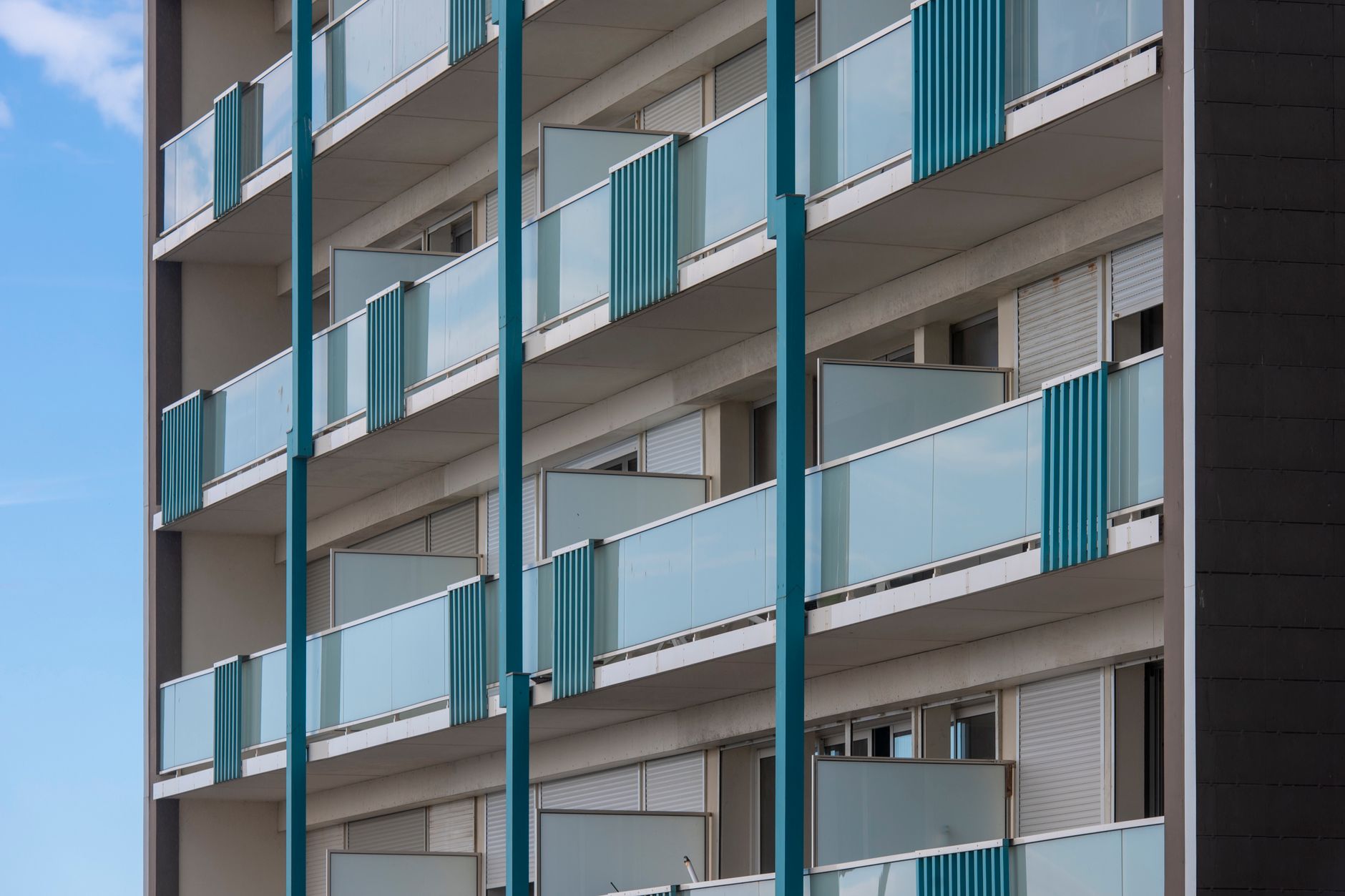 Exterior view of a modern apartment building with multiple blue balconies, showcasing contemporary architectural design.