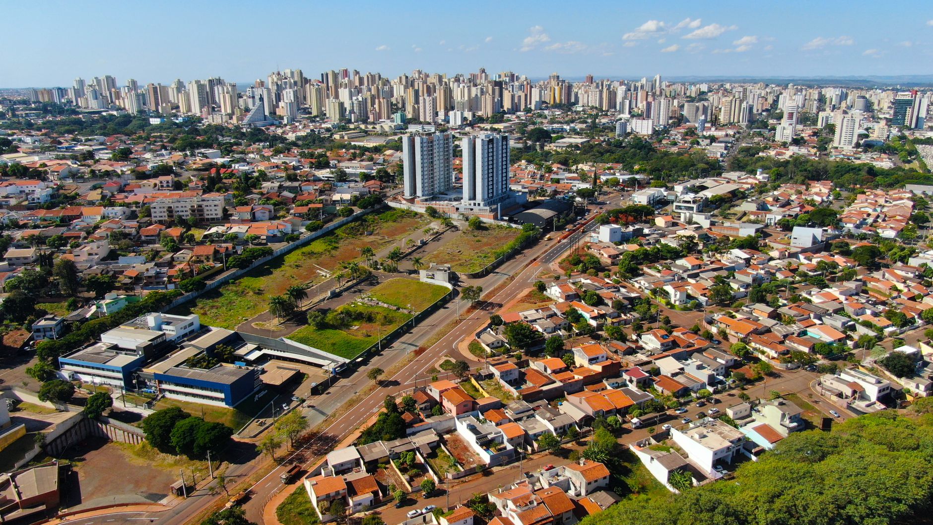 Aerial cityscape of Londrina, Brazil, showcasing buildings, houses, and greenery under a clear blue sky.