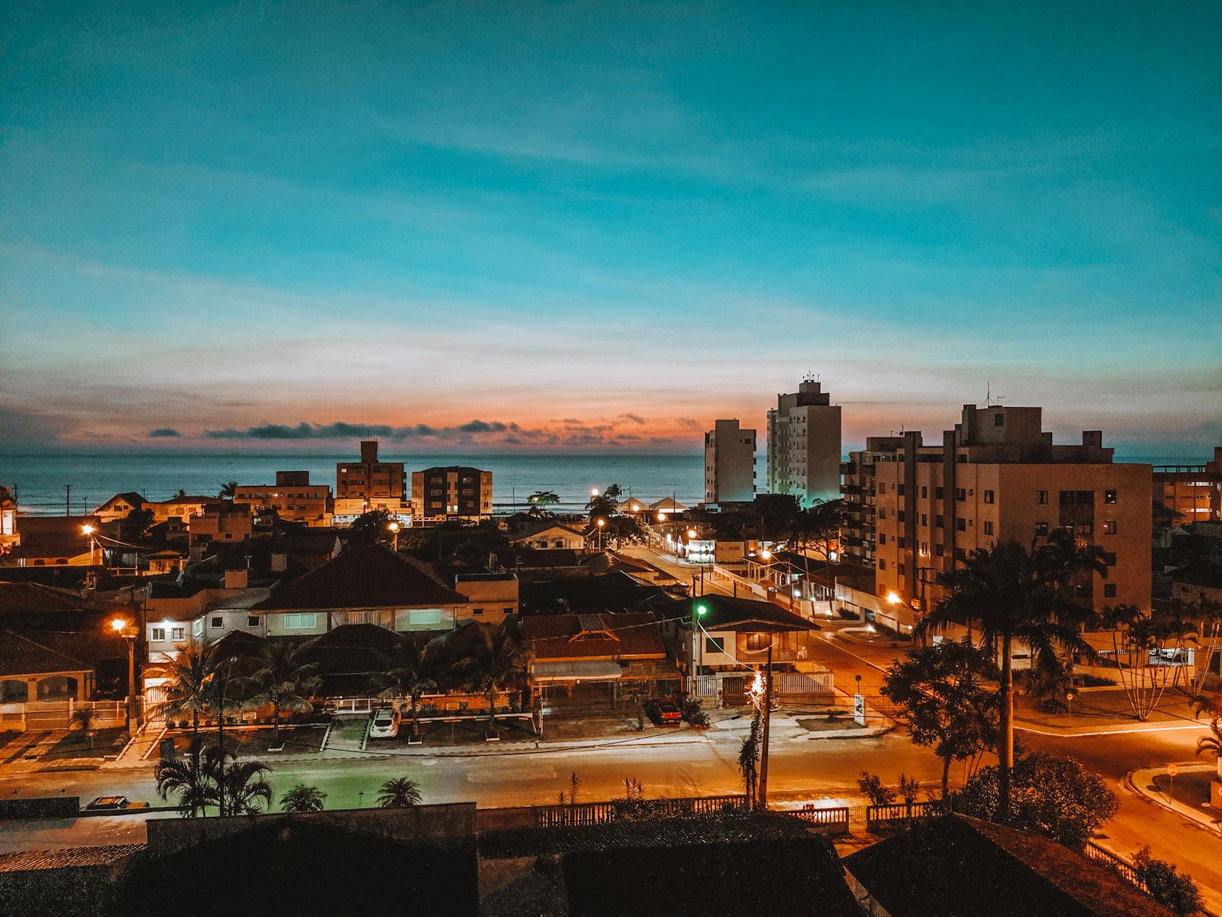 A beautiful cityscape view of Matinhos in Brazil at dusk, showcasing illuminated buildings against a vibrant sky.