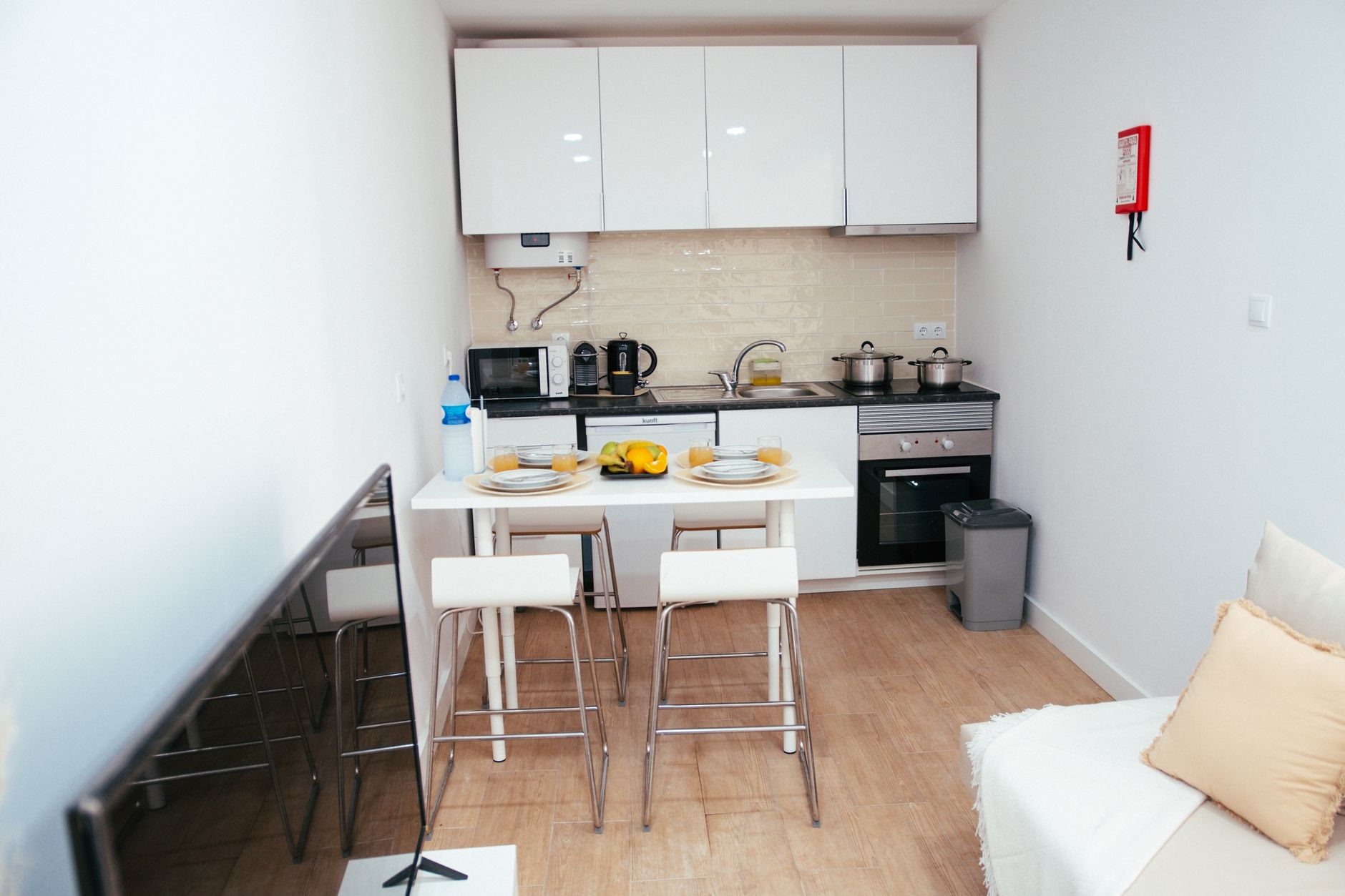 Cozy modern kitchen with appliances and seating area in a minimalist apartment.