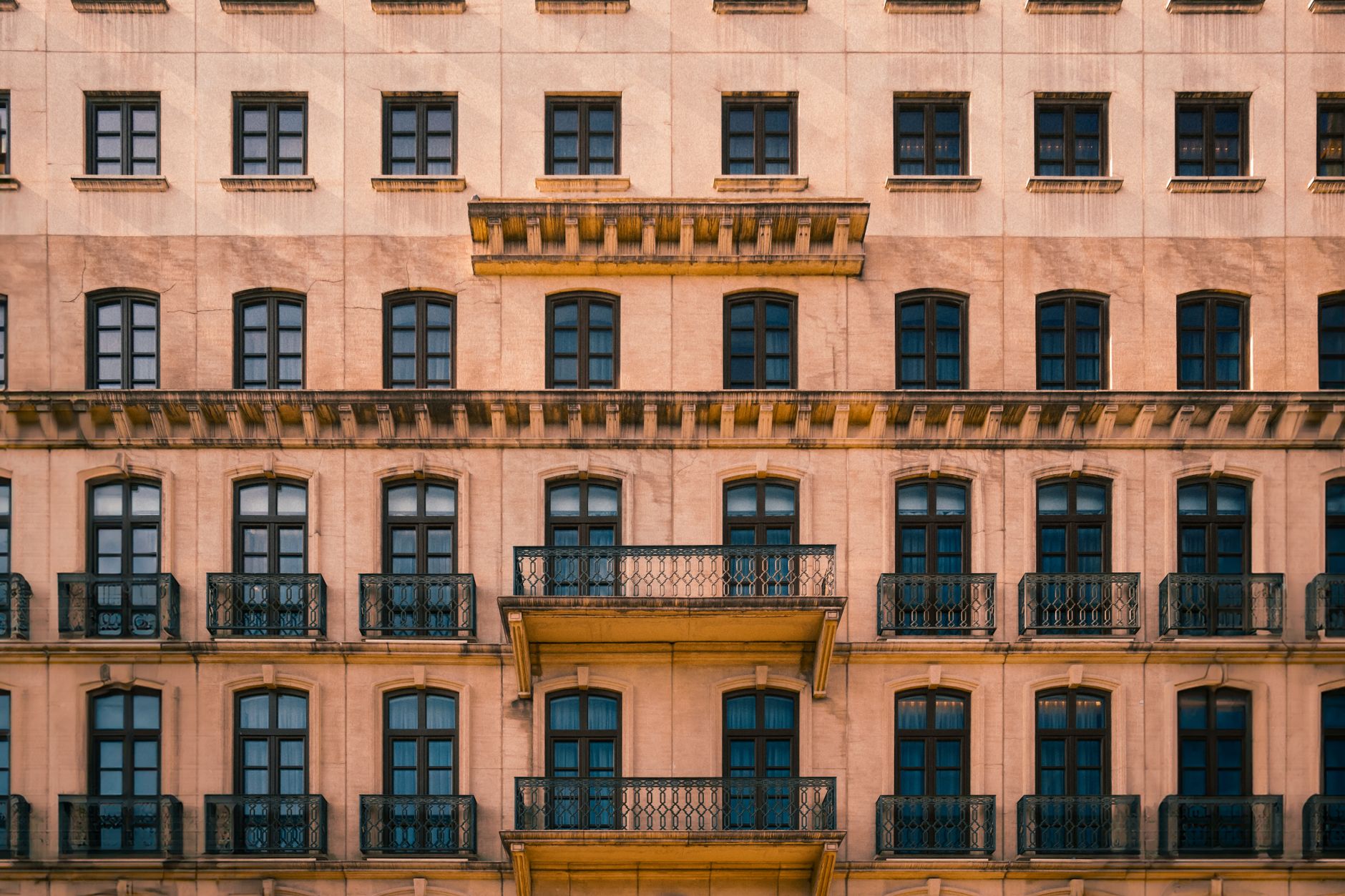 Capture of a classic building facade with symmetrical design and ornate balconies, in warm beige tones.