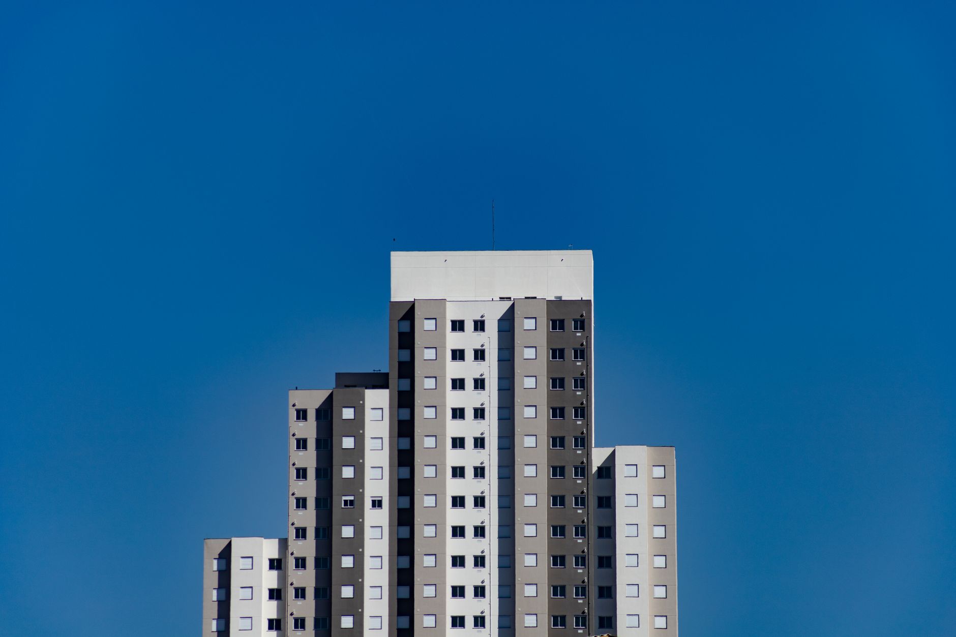 Contemporary high-rise building with geometric patterns set against a vibrant blue sky.