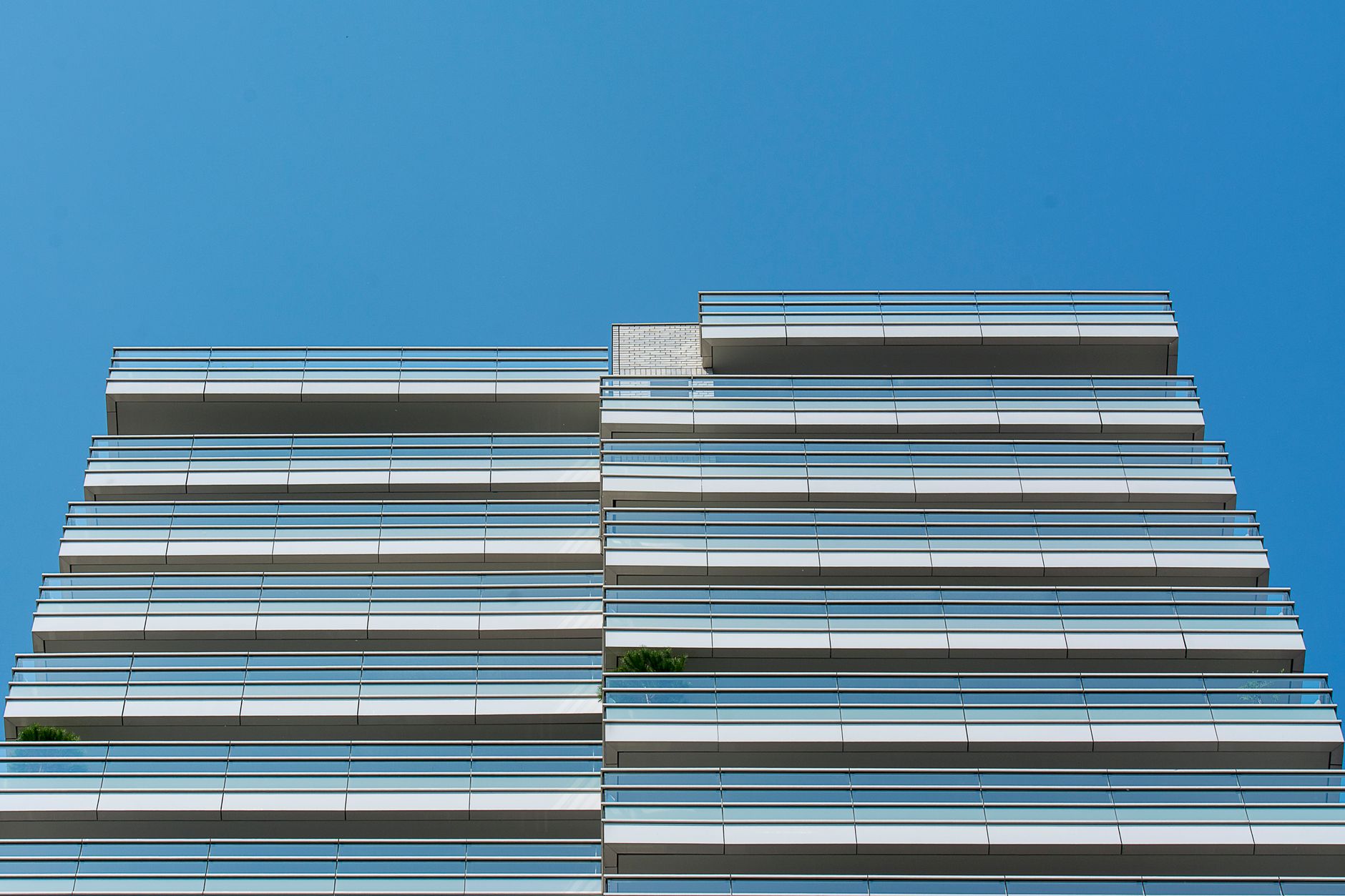 Low angle view of a modern building with glass balconies and a clear blue sky.