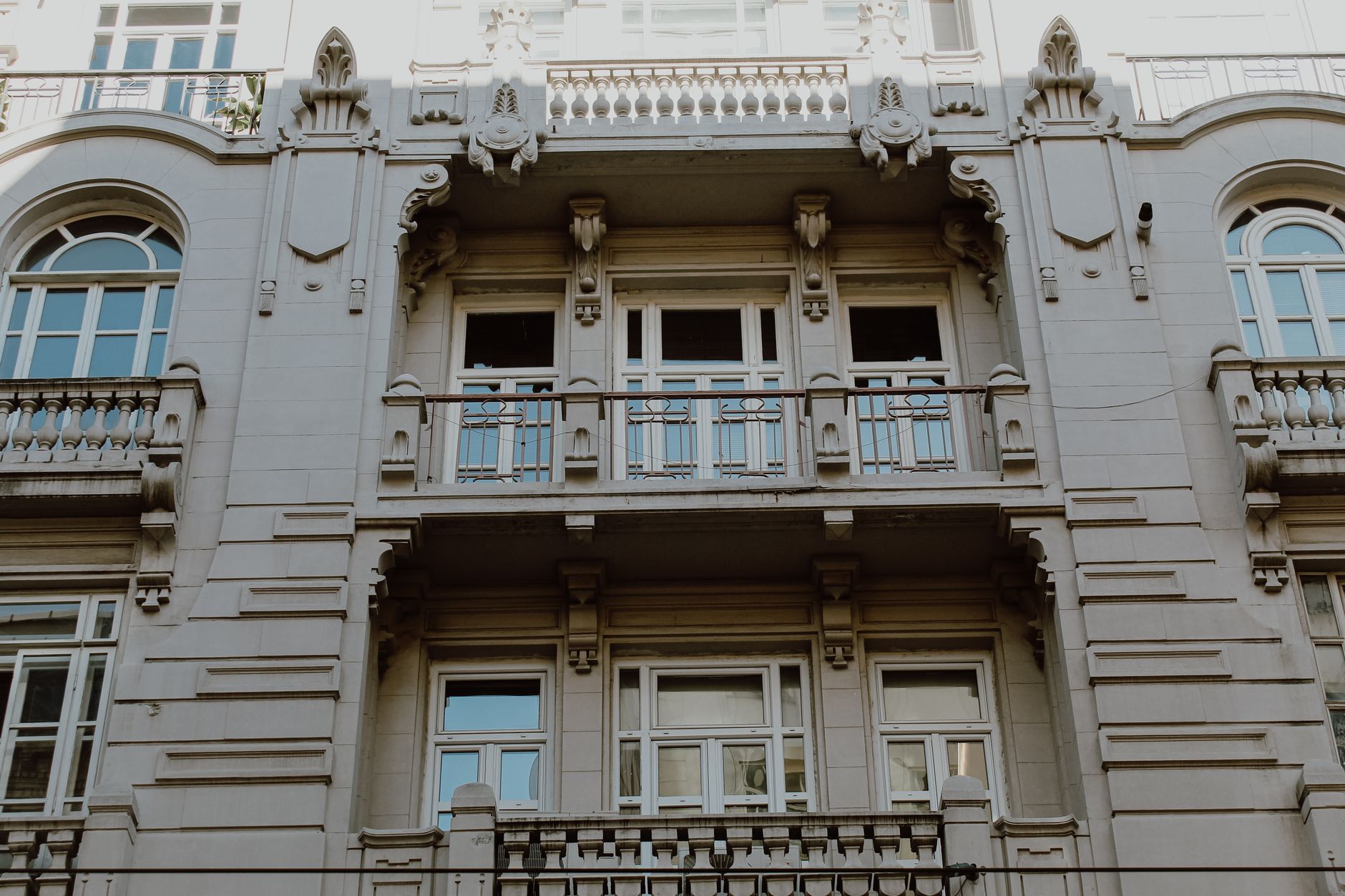 Stunning architectural facade featuring ornate balconies and large arched windows, captured in a low-angle shot.