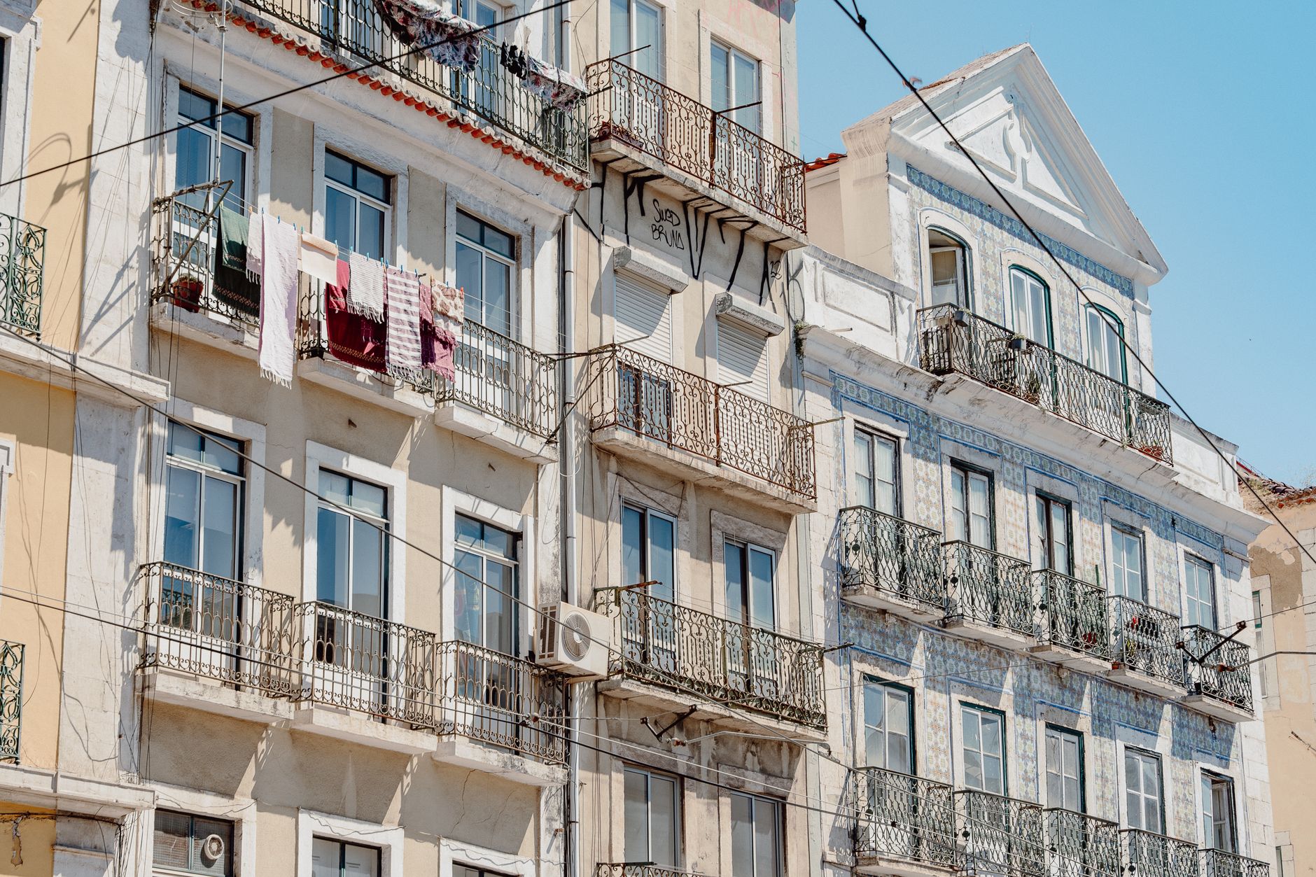 Charming Lisbon architecture with wrought iron balconies and drying laundry on a sunny day.