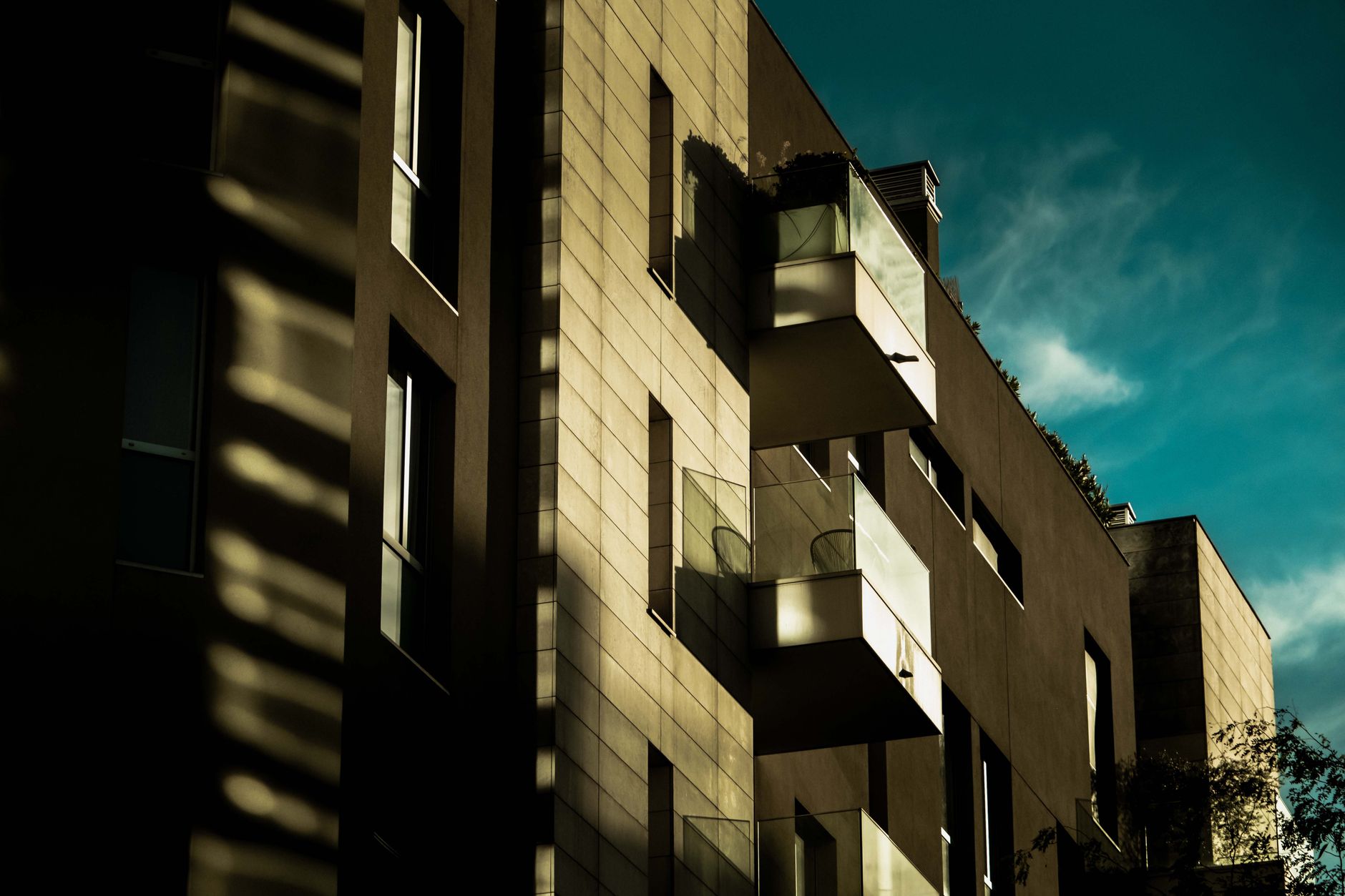 A modern building with striking shadows and balconies under a vibrant sky.
