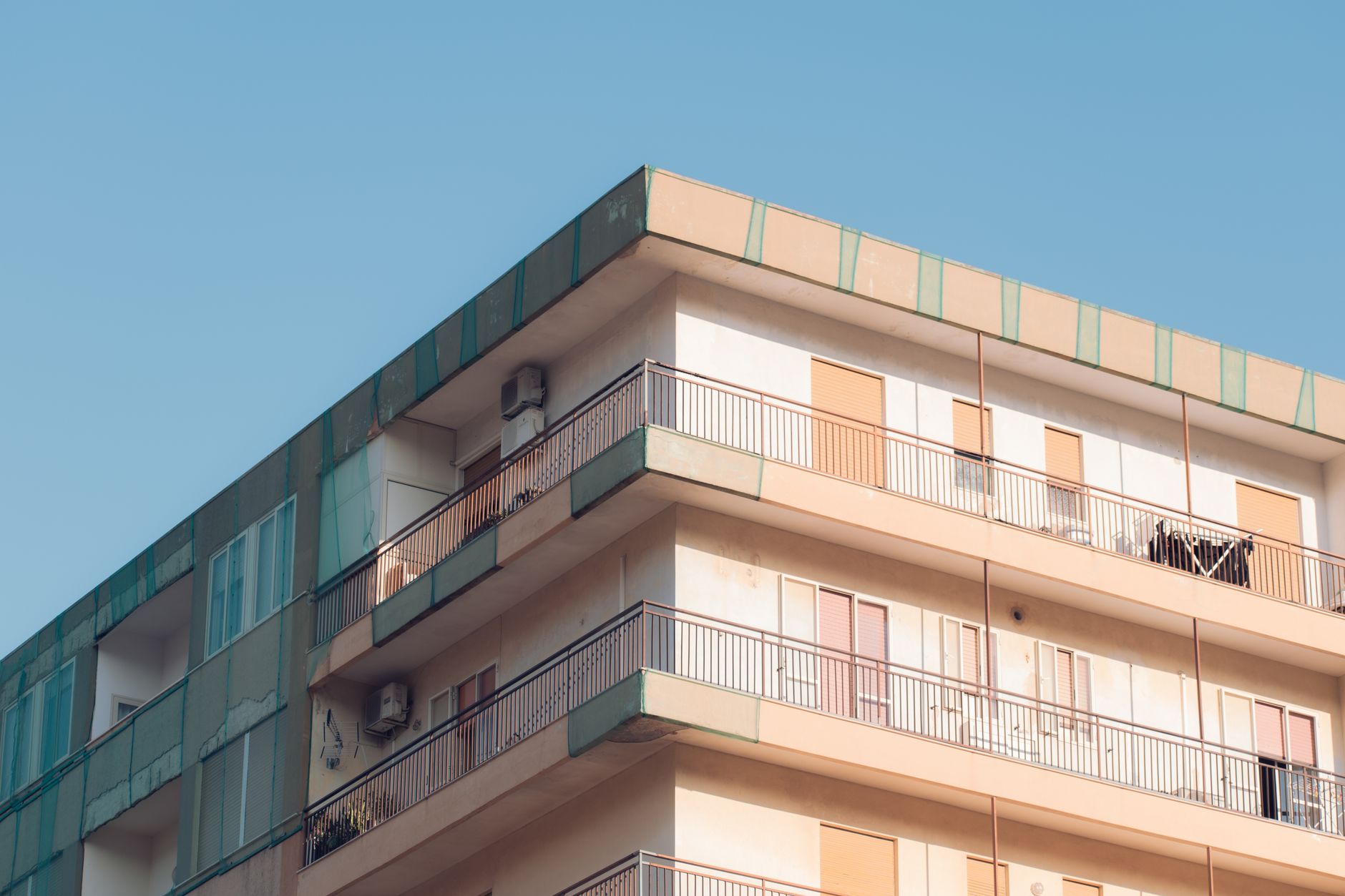 Sunlit balconies of a modern residential building in Avola, Sicily, showcasing urban architecture.