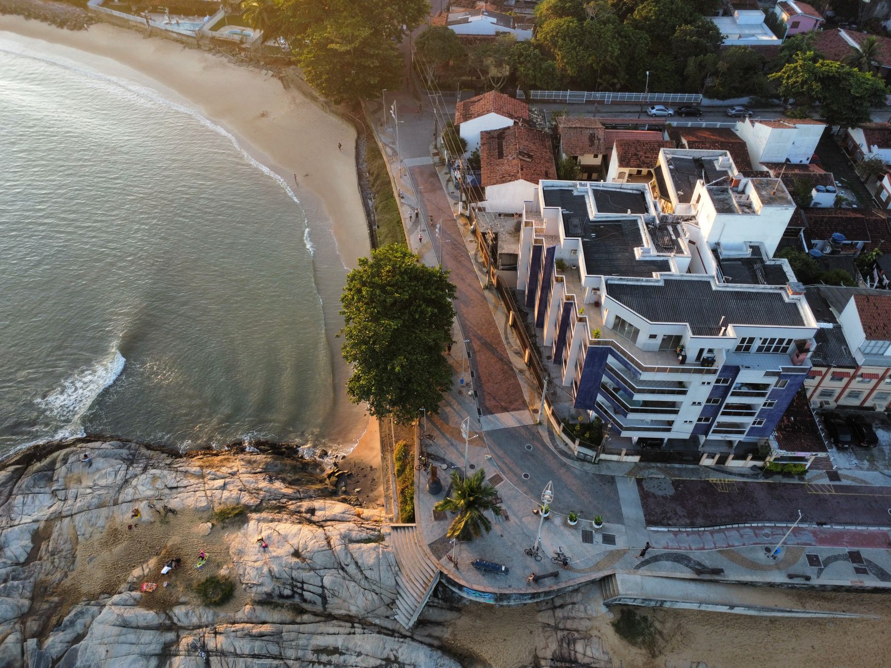 A breathtaking aerial shot of a coastal resort with rock formations and a serene beach at sunset.